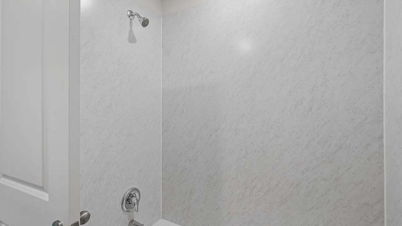 Shower with white textured walls and chrome fixtures