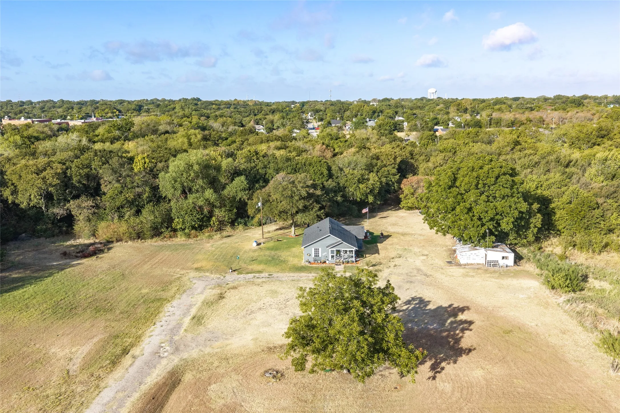 Expansive property featuring a single-story residence, a detached auxiliary structure, and mature trees