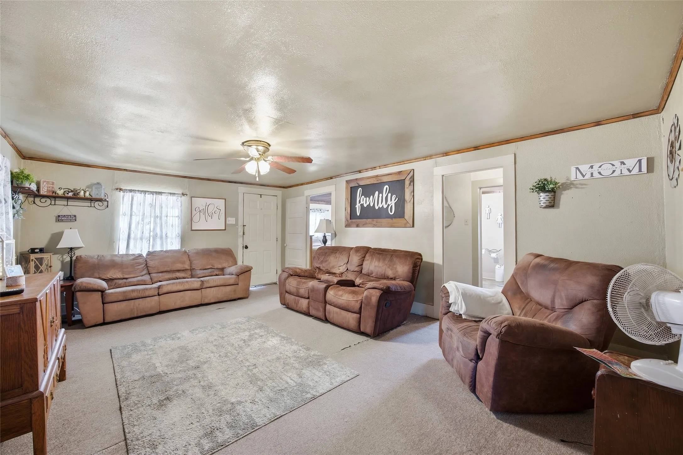 Carpeted flooring, ceiling fan with integrated lighting, window with privacy sheers, interior door with hardware, and additional doorway