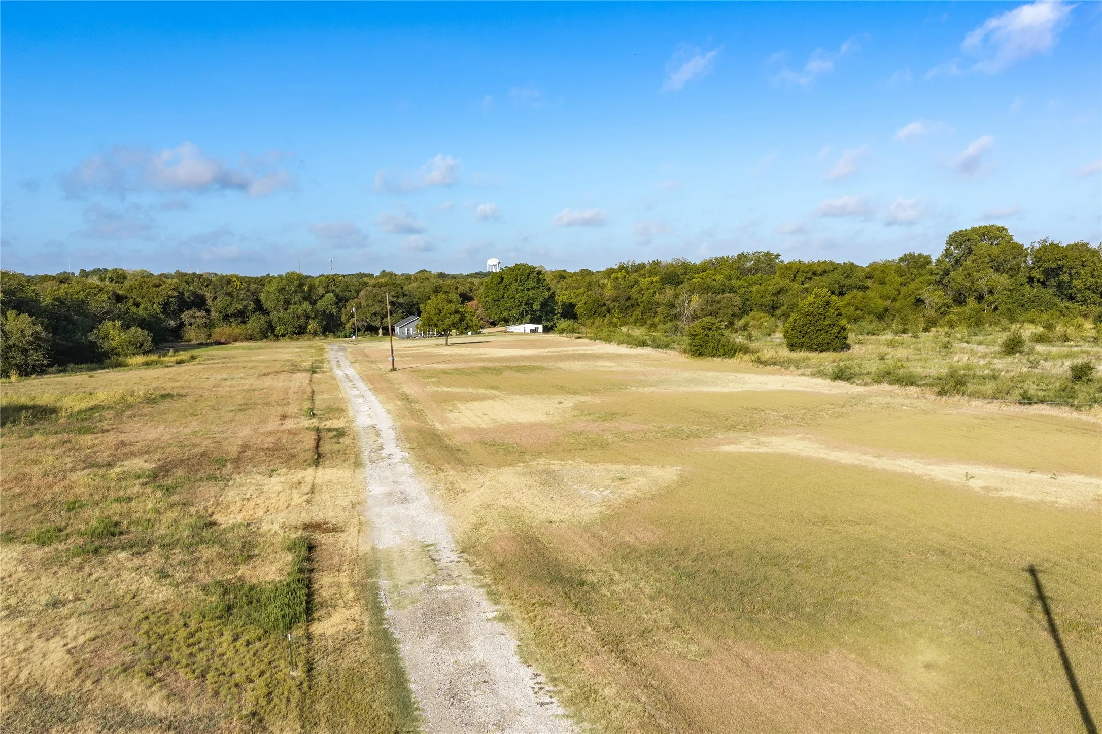Expansive land with a gravel drive, surrounded by mature trees
