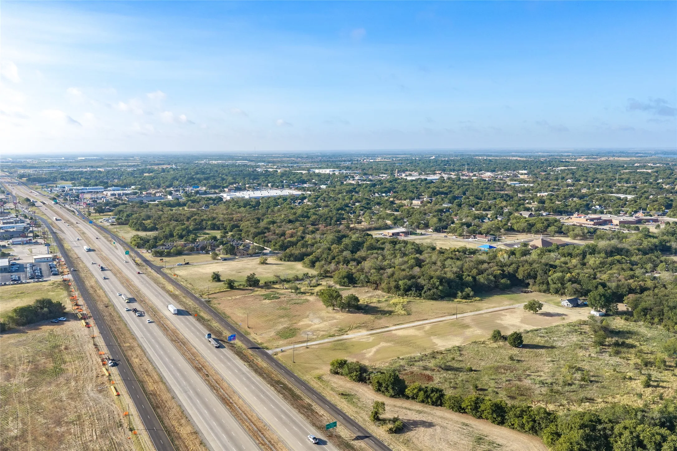Expansive undeveloped land featuring a highway frontage, mature tree lines, and open clearings