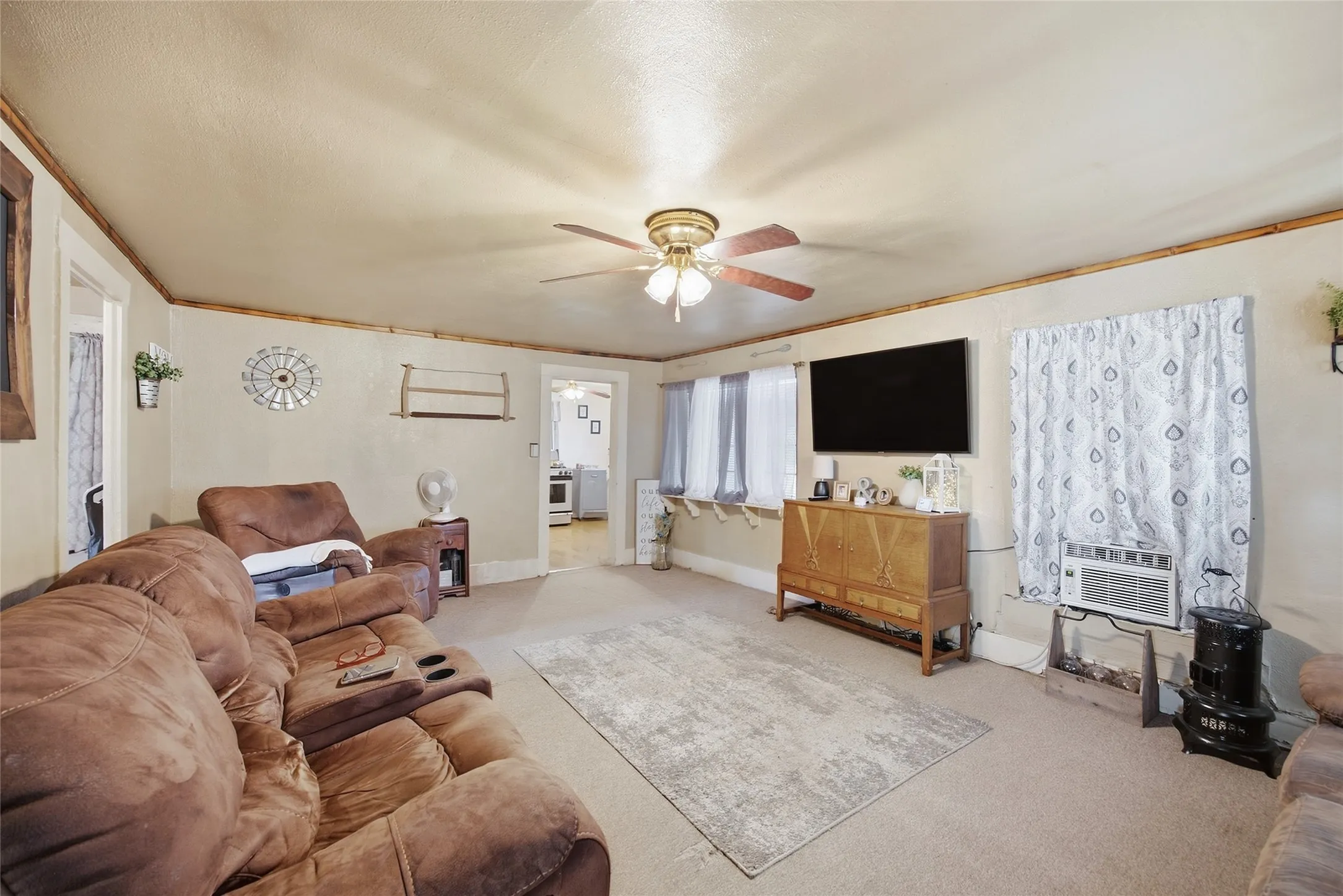 Carpeted flooring, ceiling fan, and window-mounted air conditioning unit