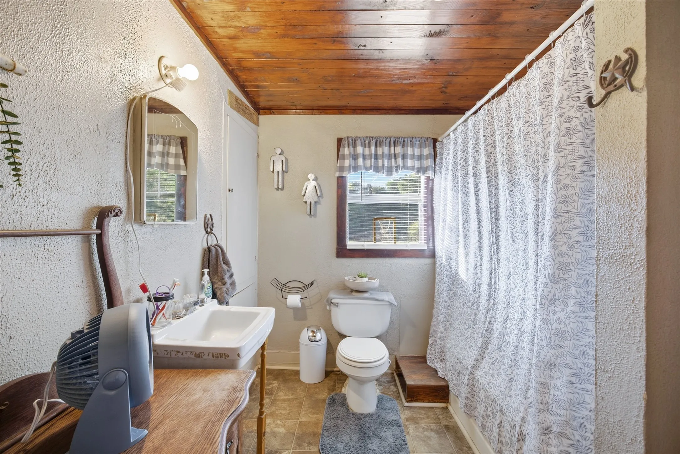 Bathroom featuring a wood-panel ceiling, textured wall finish, and a window with blinds