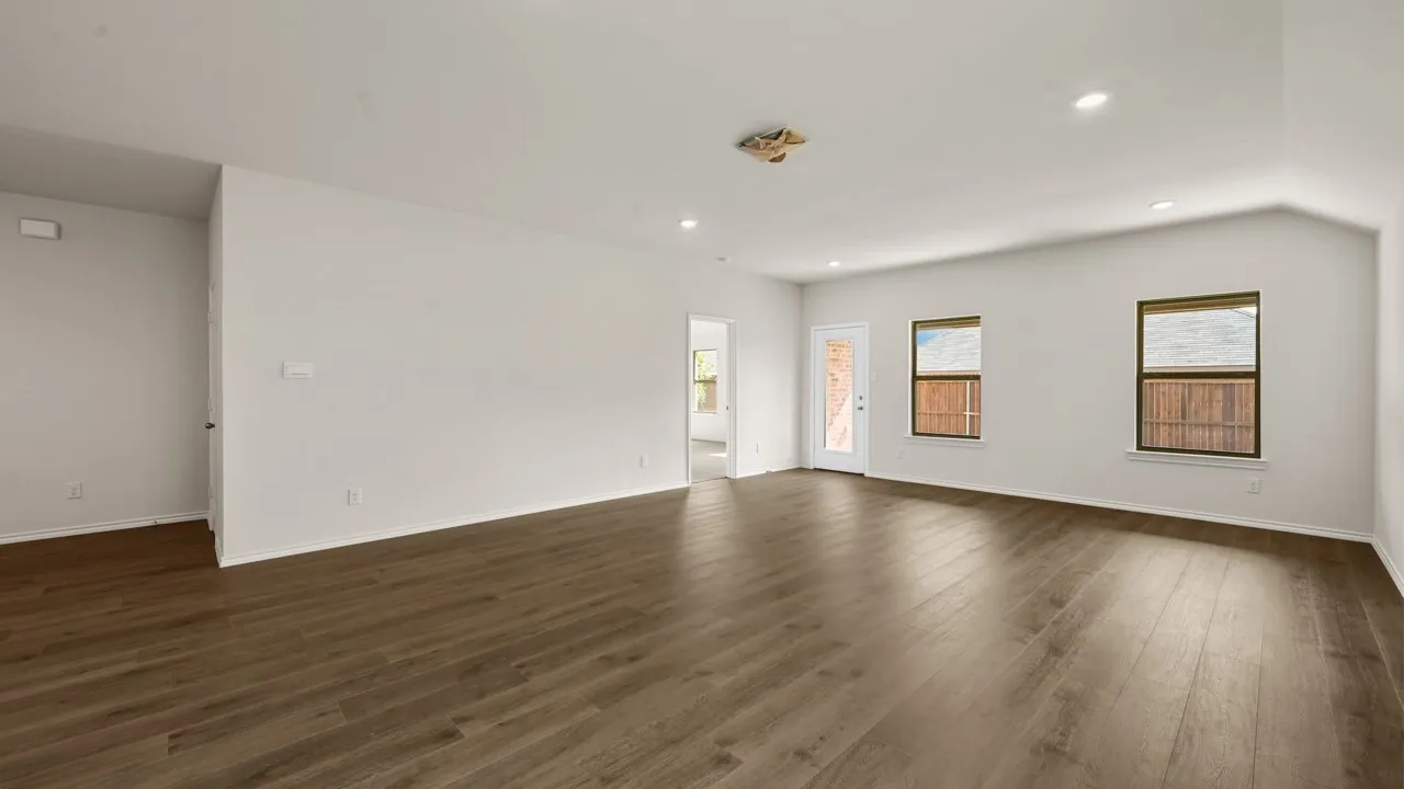 Expansive room featuring wood-finish flooring, recessed lighting, multiple windows, and a glass-paneled door
