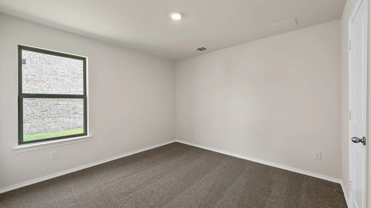 Recessed ceiling lighting, neutral wall paint, dark grey carpeting, and a white interior door