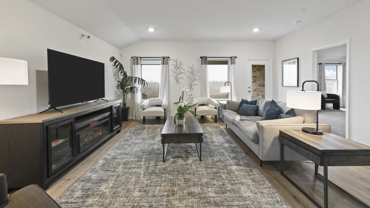 Spacious living area featuring wood-finish flooring, recessed lighting, and large windows with white drapes