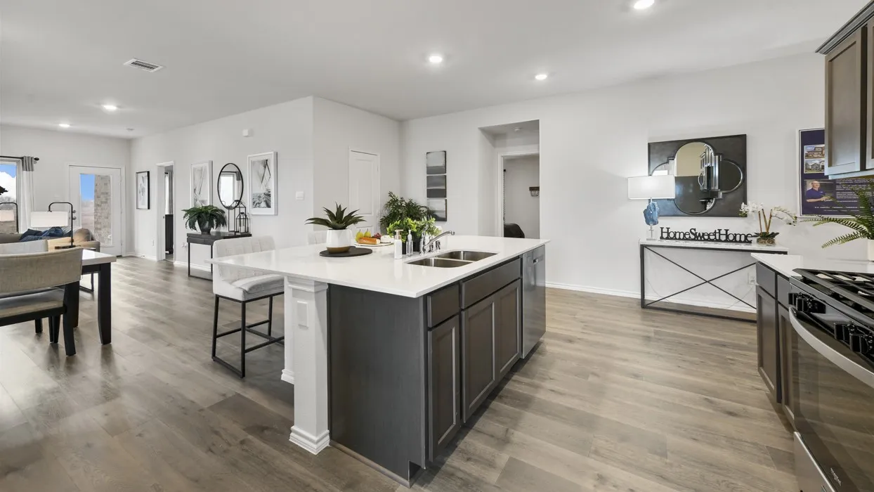 Open-concept living area featuring wood-finish flooring, a kitchen island with seating, recessed lighting, and stainless steel appliances