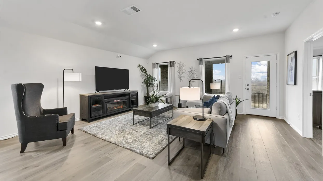 Spacious living area featuring light wood-finish flooring, vaulted ceilings, and recessed lighting