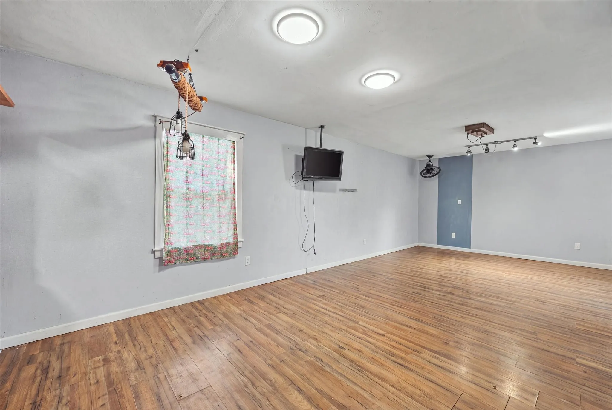 Wood-finish flooring with light-colored walls and a window