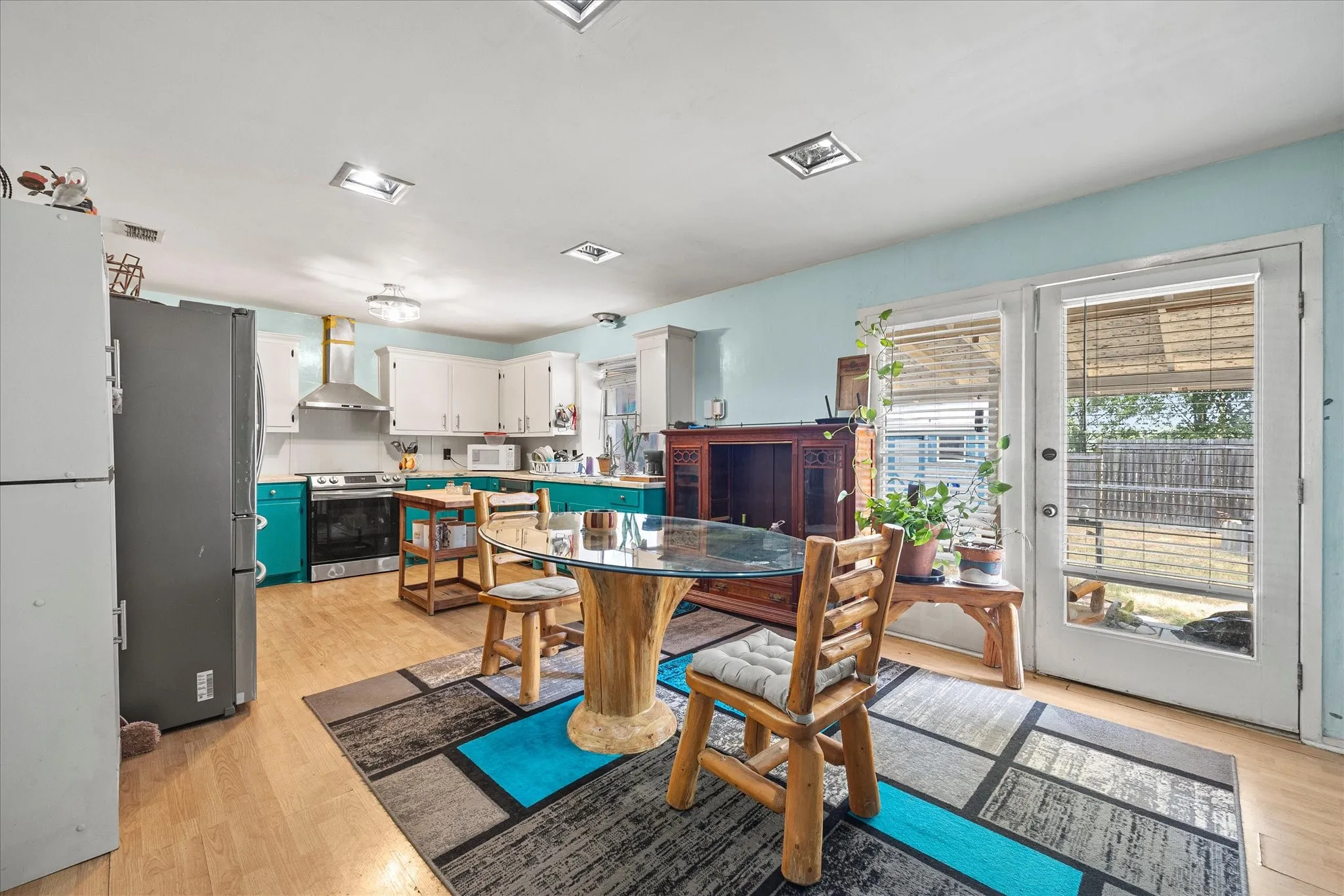 Kitchen featuring wood-finish flooring, white cabinetry, a stainless steel range hood, and a glass-paneled exterior door