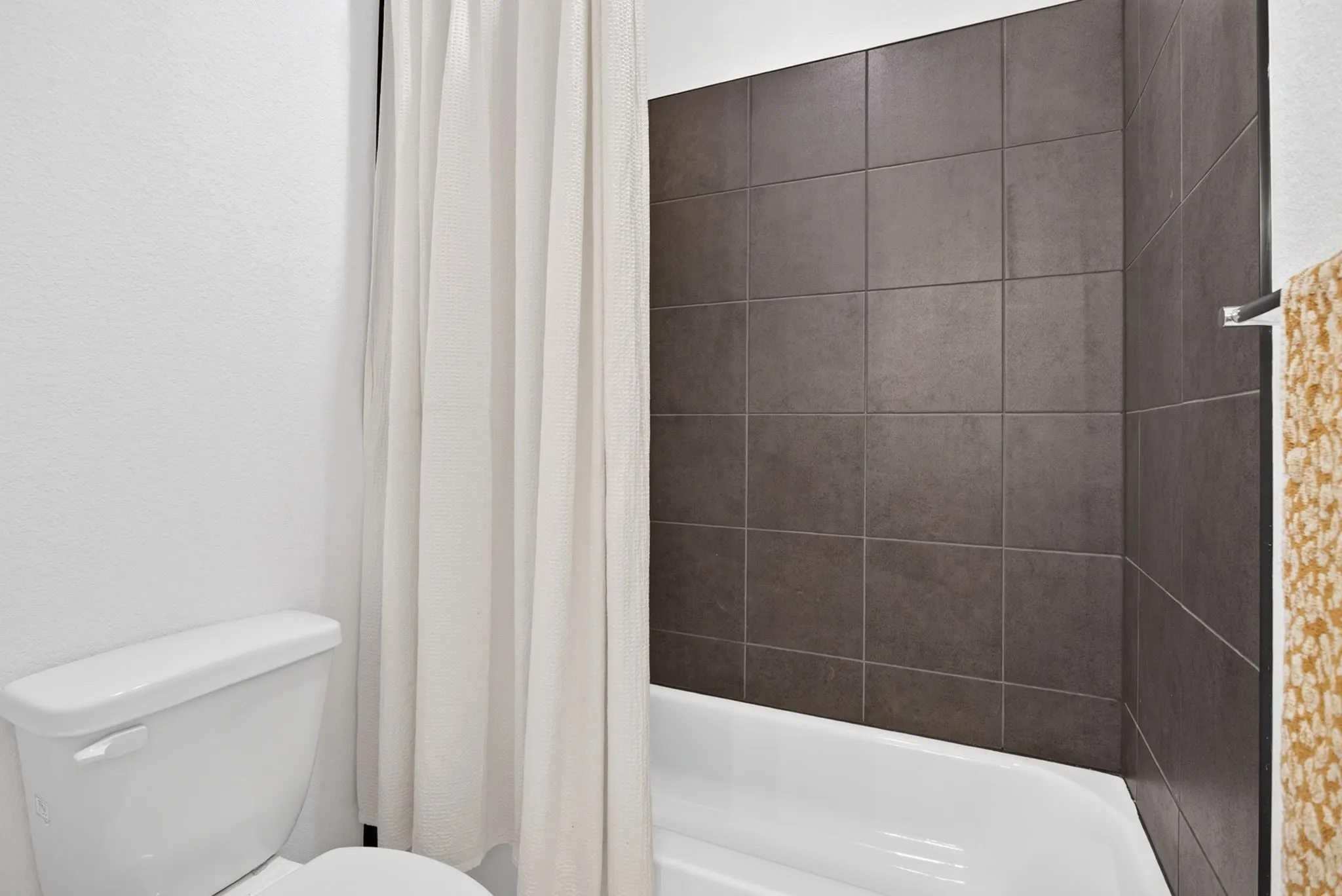 Separate wet area with toilet and tiled tub-shower combo.