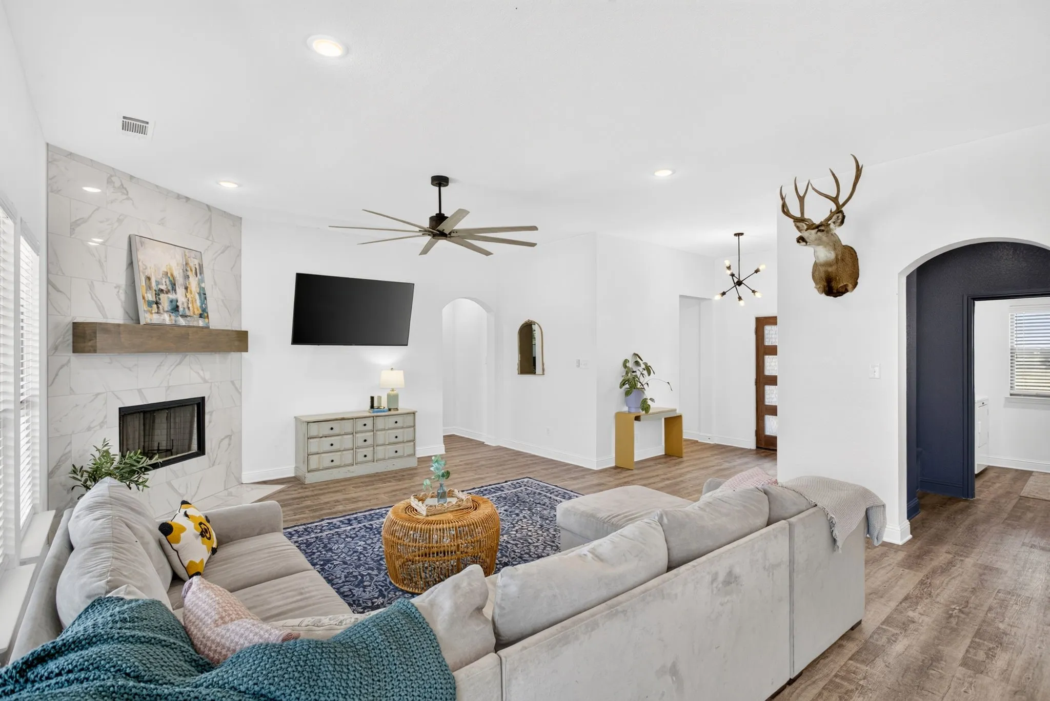 Arched entry by the TV leads to primary; arched entry on right leads to mud nook, laundry room and garage.