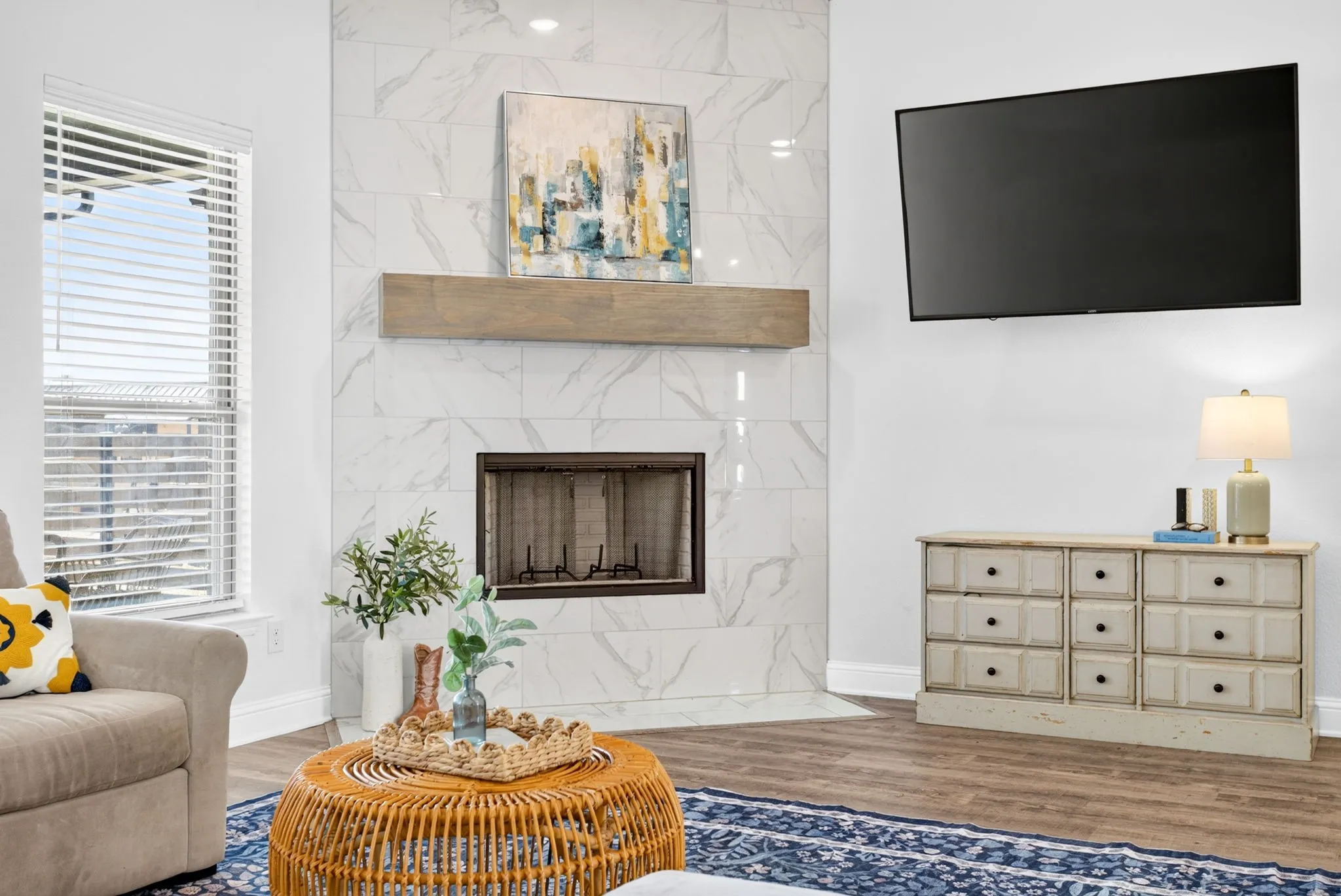 Wood burning fireplace with marble-look tile surround to the ceiling. Clean, simple, chic.