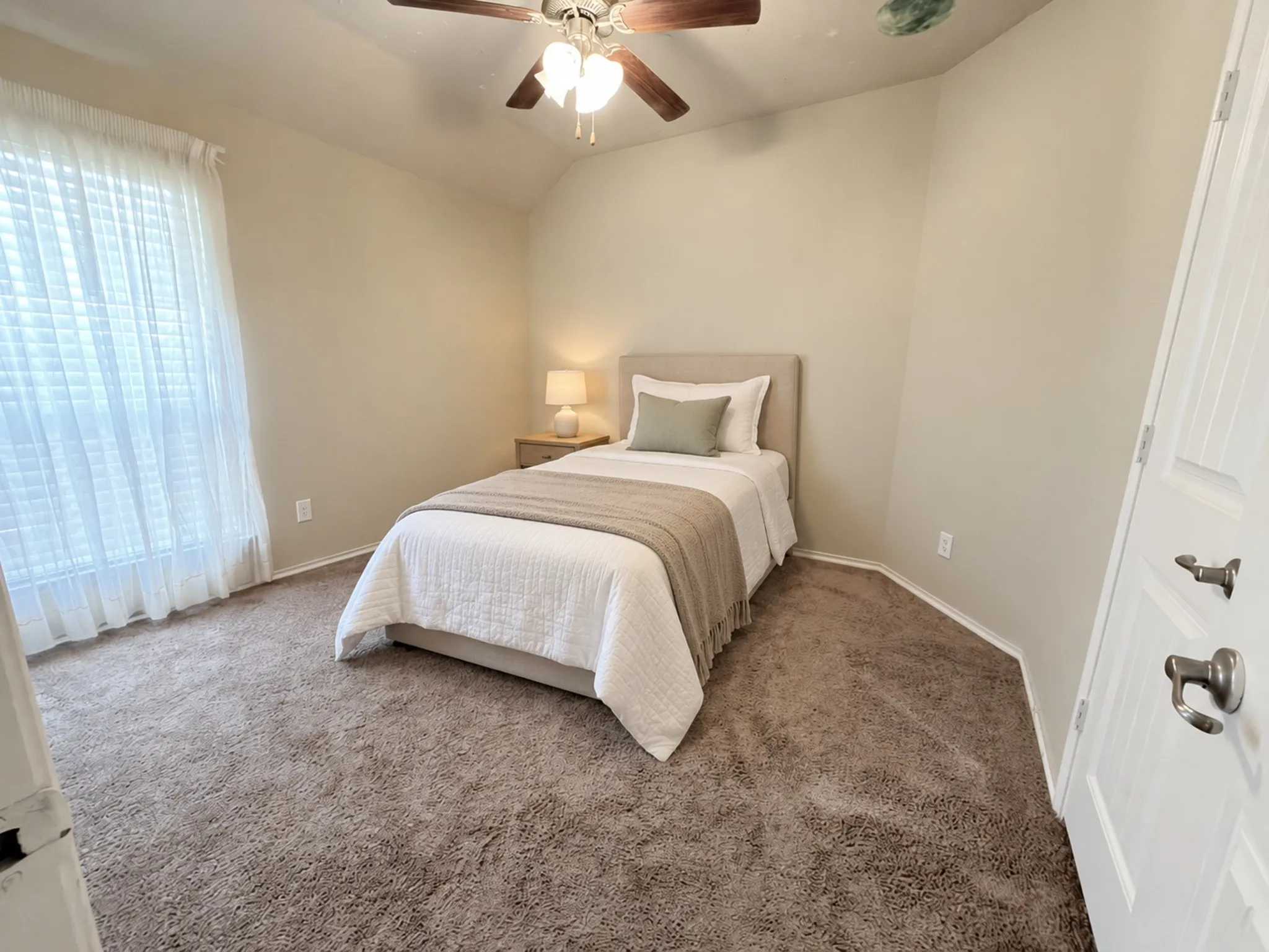 Vaulted ceiling room with plush carpeting, a ceiling fan, and window with white blinds VIRTULY STAGED