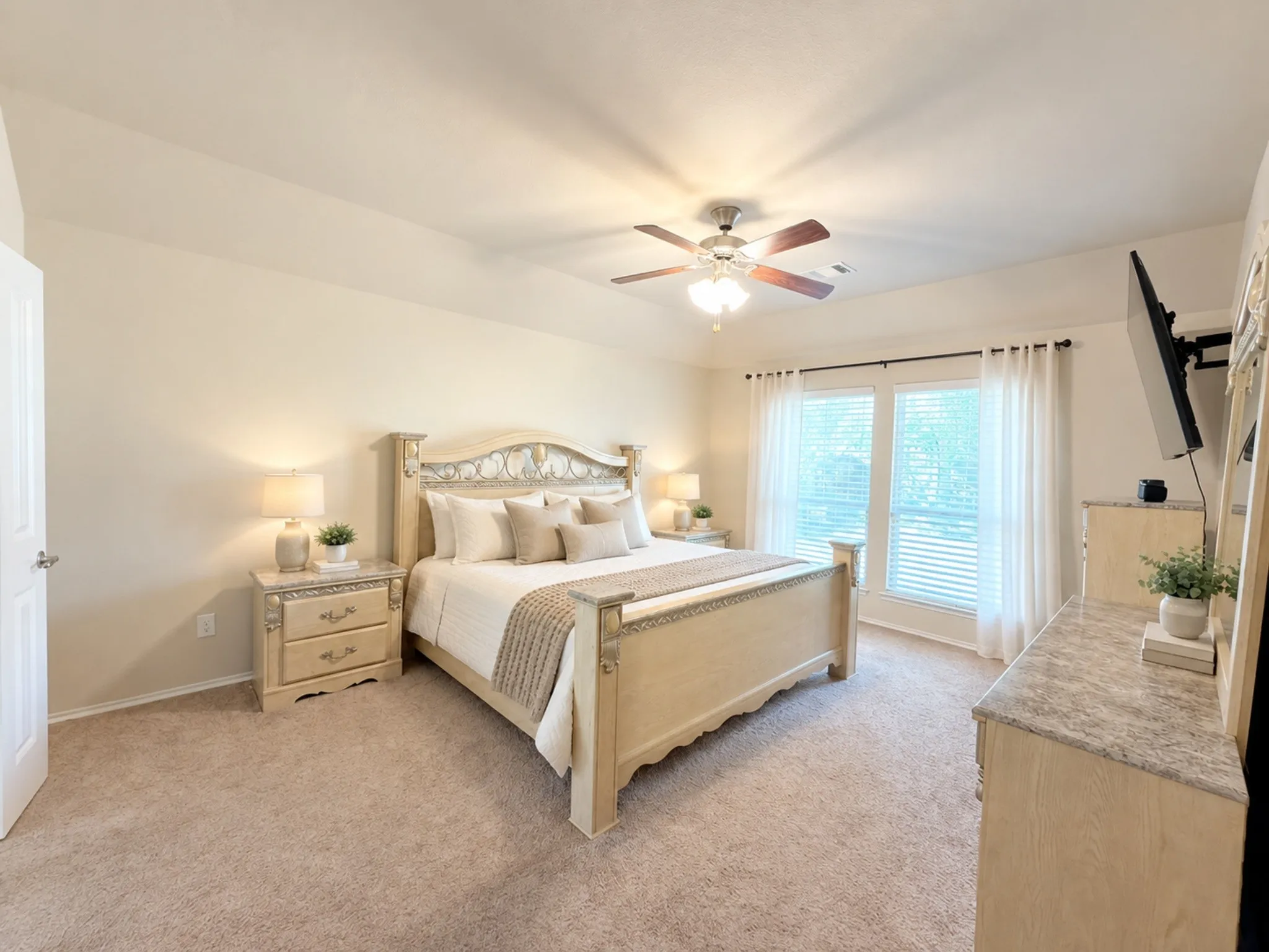 Neutral-toned carpeting, ample natural light through large windows, ceiling fan with integrated lighting, and a tray ceiling. VIRTULY STAGED
