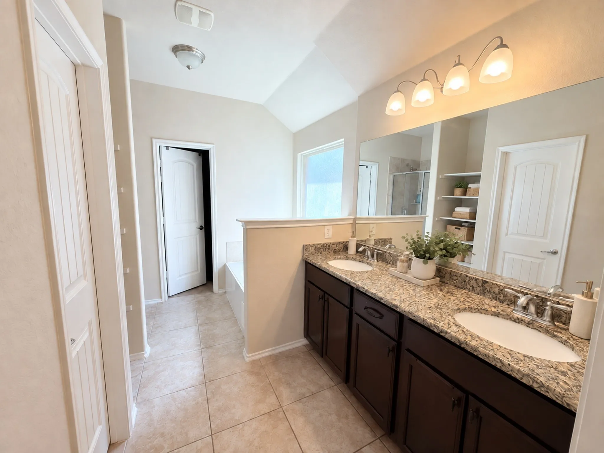 Dual vanity with granite-style countertop, undermount sinks, and dark wood-finish cabinetry