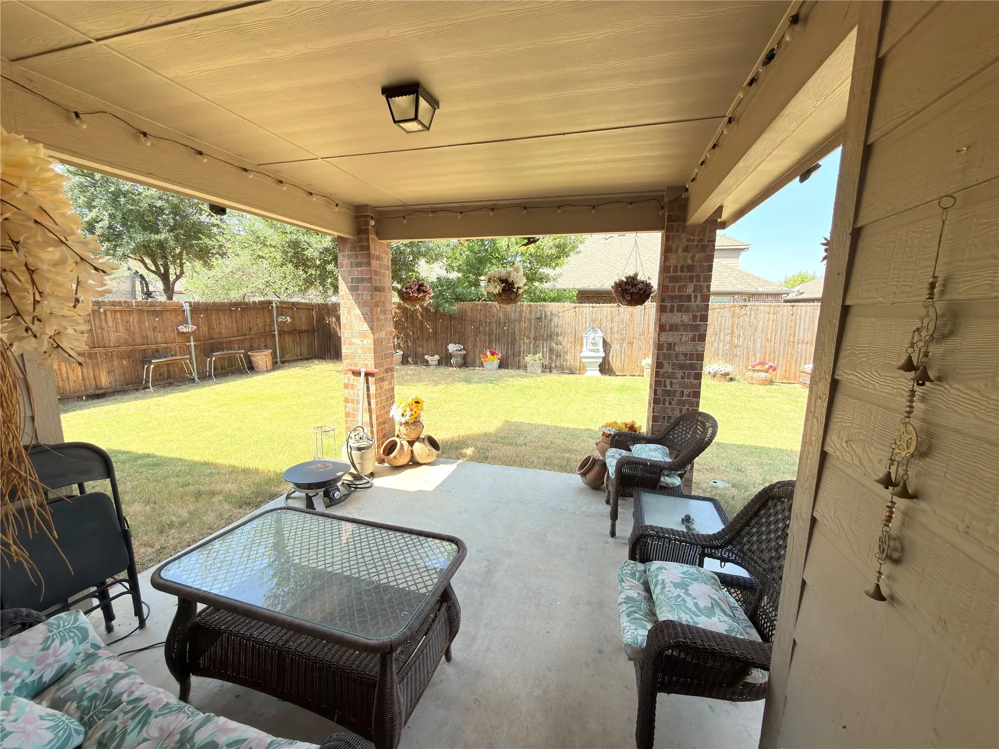 Covered patio with a concrete surface, brick columns, and a fully fenced grassy yard