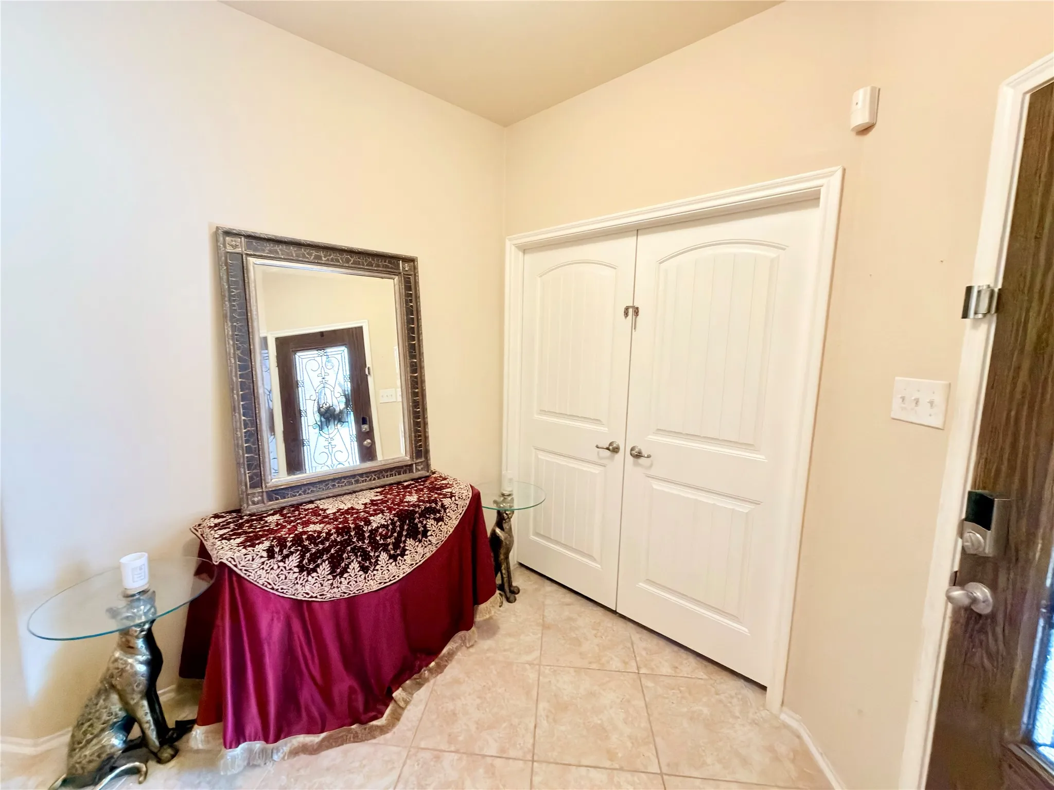 Tile flooring, arched panel interior doors, and a wood-finish entry door with decorative glass