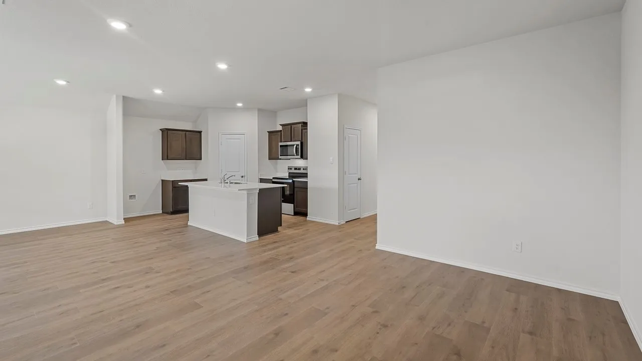 Spacious room featuring wood-finish flooring, recessed lighting, and white walls