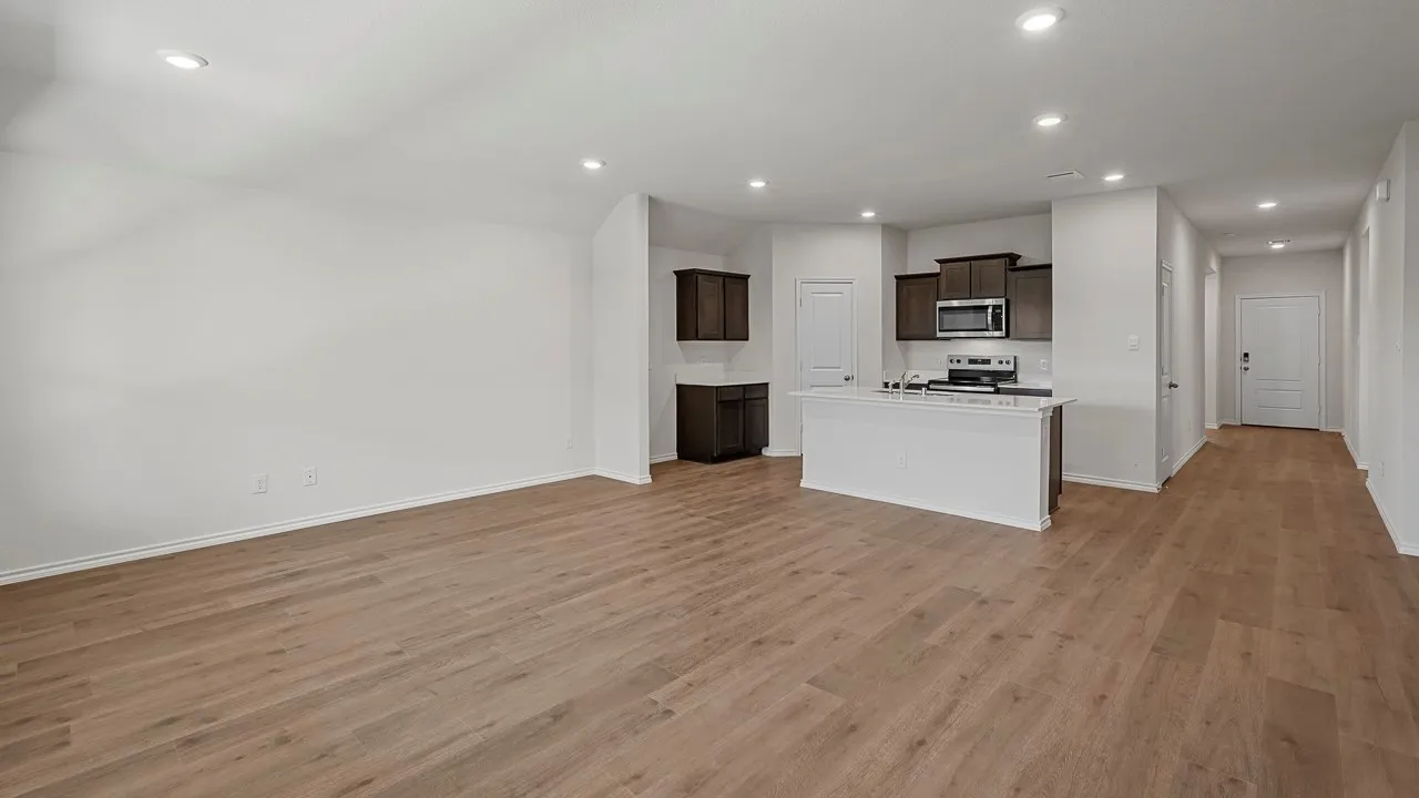 Open-concept living area with wood-finish flooring, recessed lighting, and a kitchen island with white stone countertop