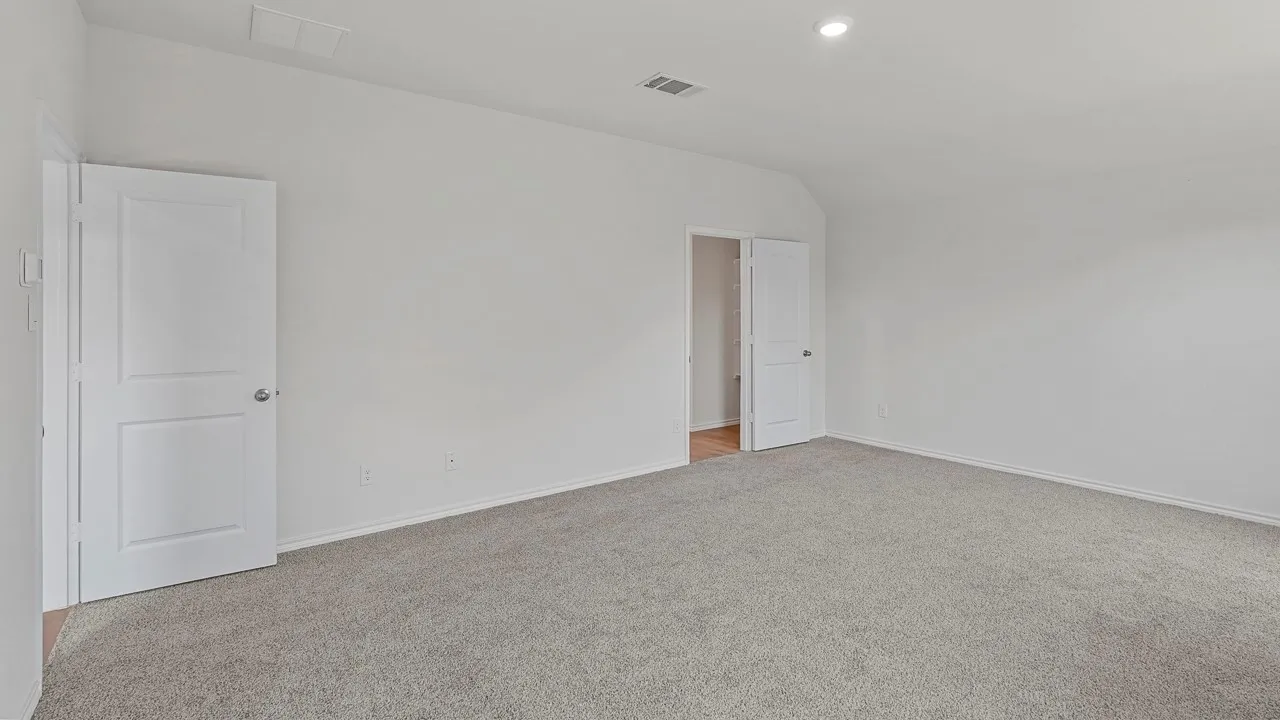 Recessed lighting illuminates a carpeted room featuring white walls and white two-panel doors