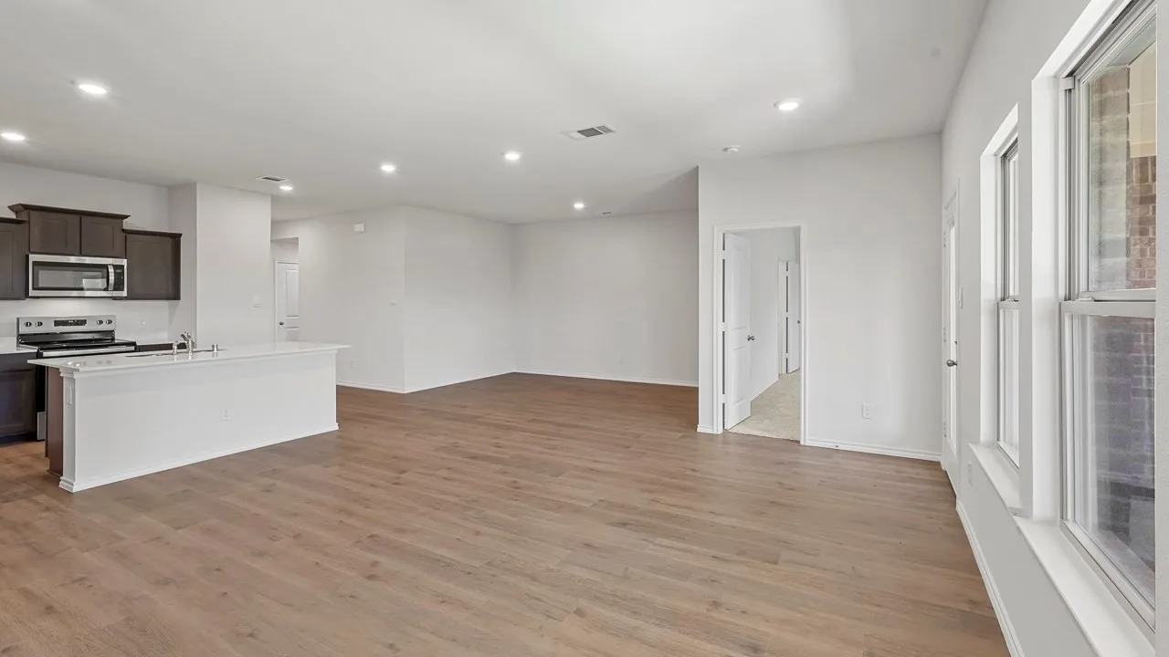 Open-concept living area with wood-finish flooring, recessed lighting, and a kitchen island with seating space