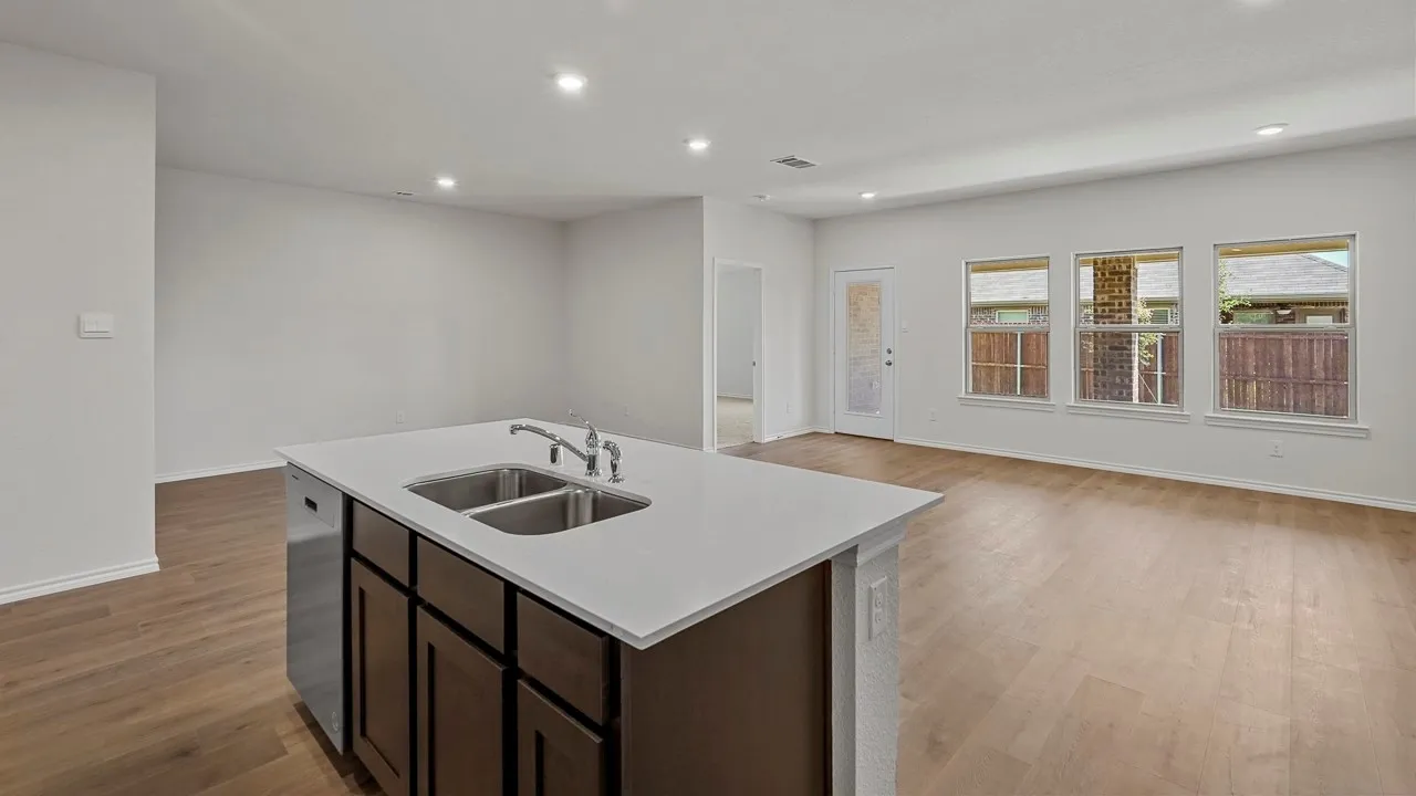Kitchen island with integrated stainless steel double sink, white countertop, dark wood-finish cabinetry, wood-finish flooring, and recessed lighting