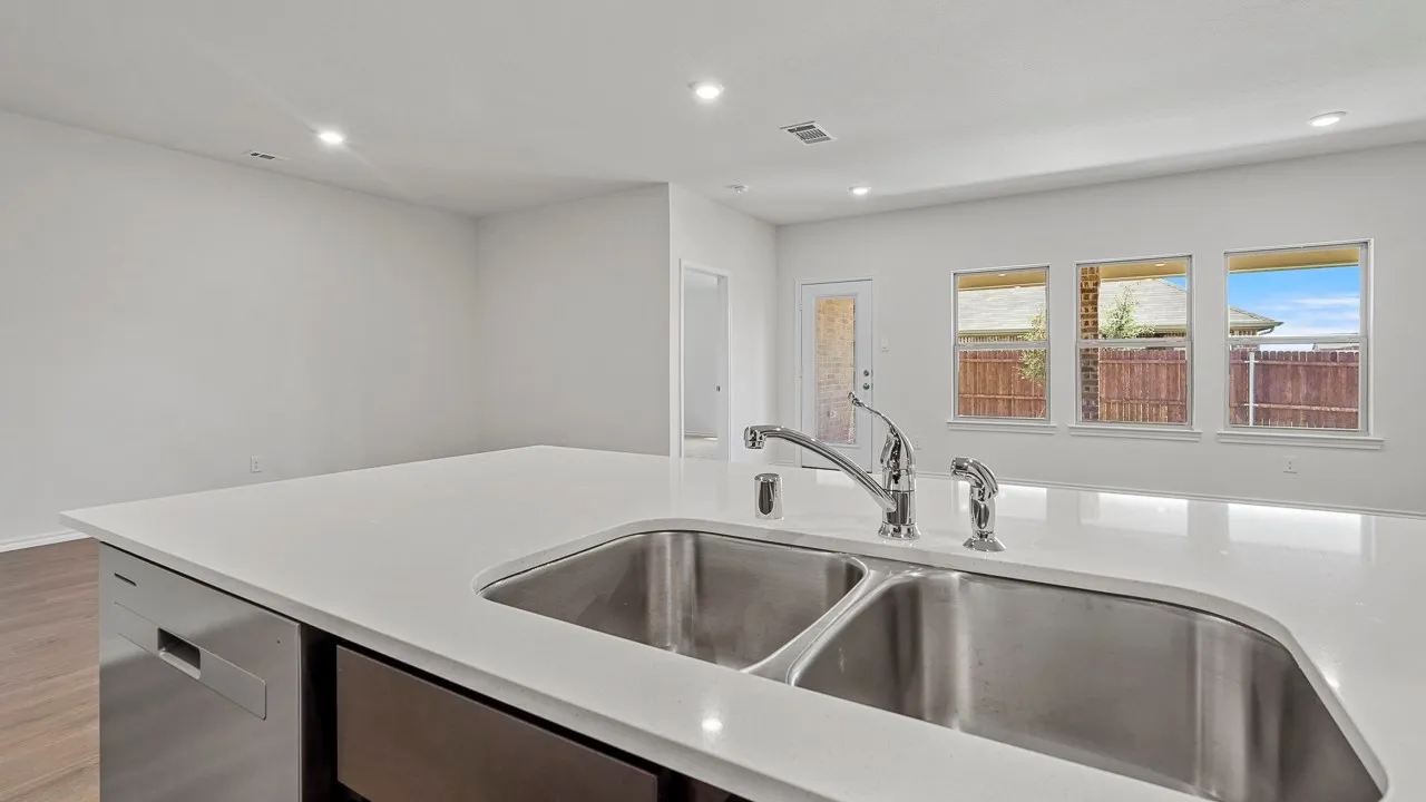 Kitchen island featuring a double basin stainless steel sink, chrome faucet, and integrated dishwasher