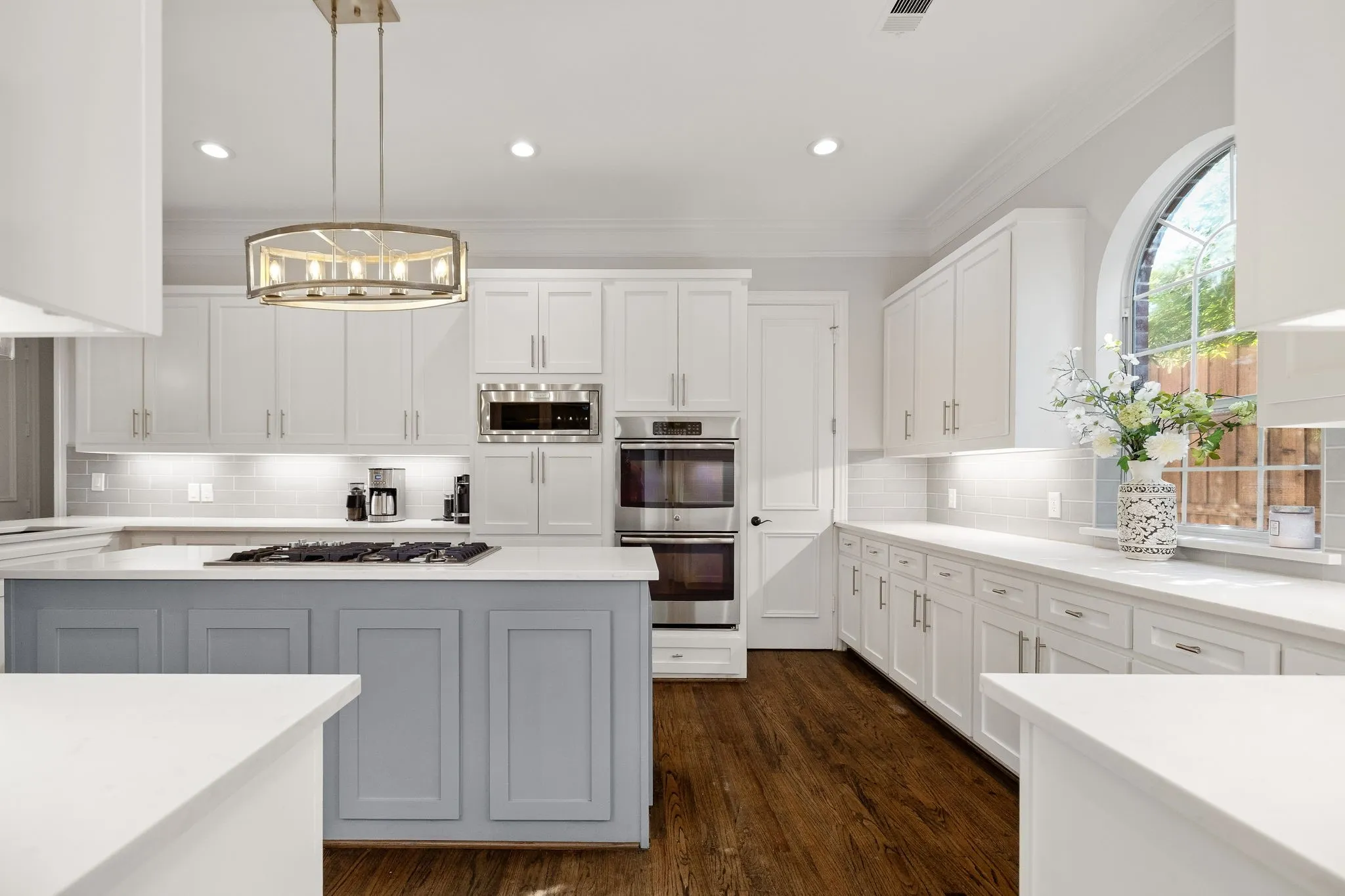 White quartz counters, custom cabinetry with spice storage, double ovens, built-in microwave.