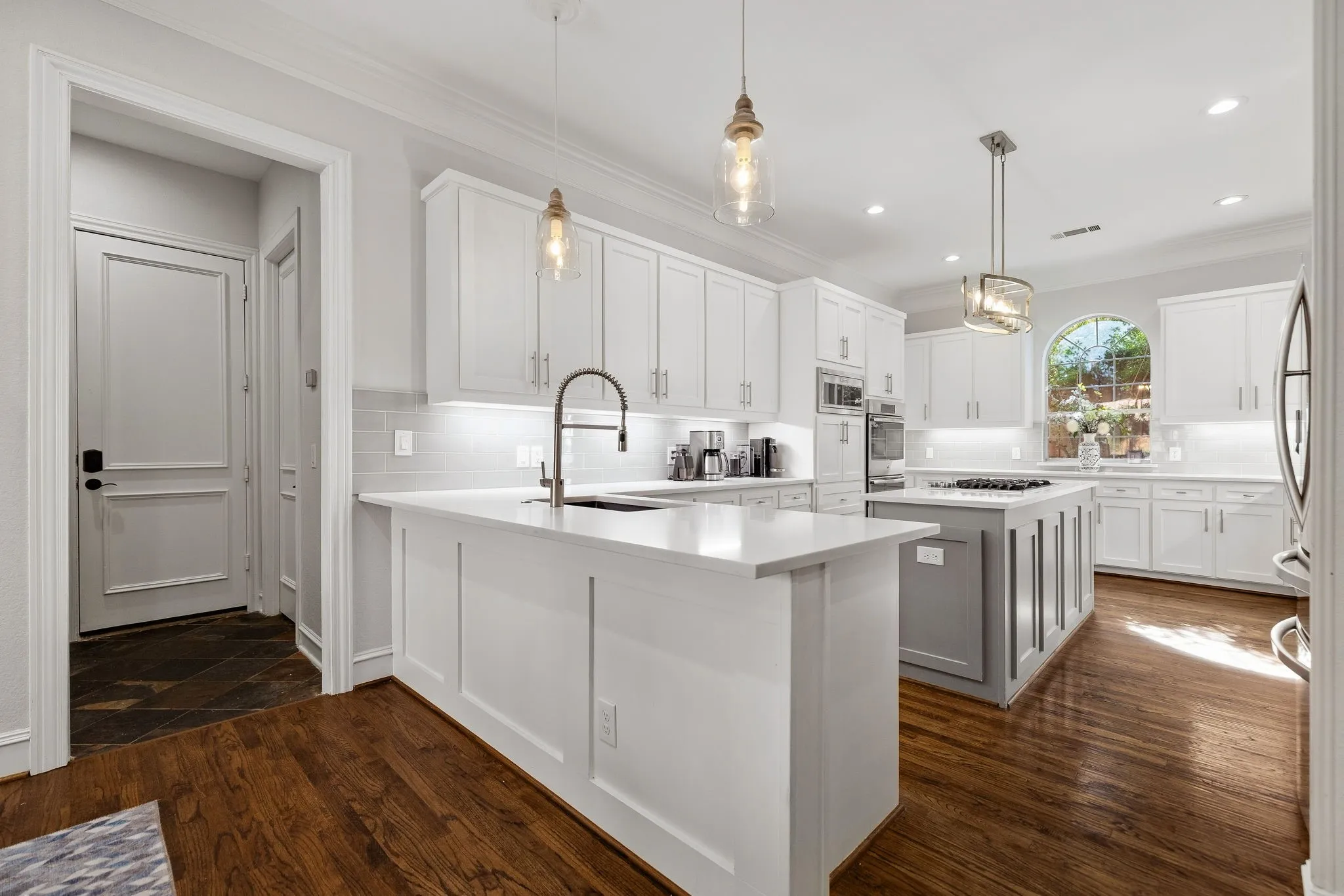 Stunning kitchen remodel including decorative lighting & hardwood flooring.
