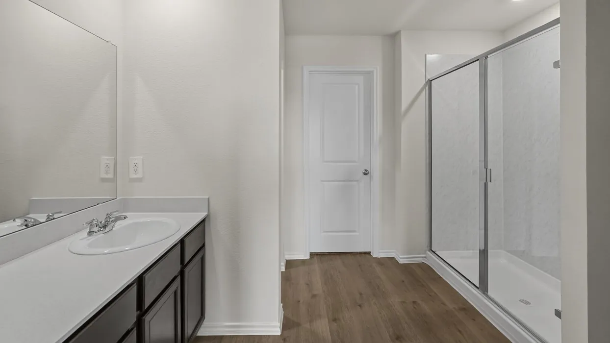 Bathroom featuring a dark wood-finish vanity with an integrated sink, polished chrome faucet, and expansive wall mirror