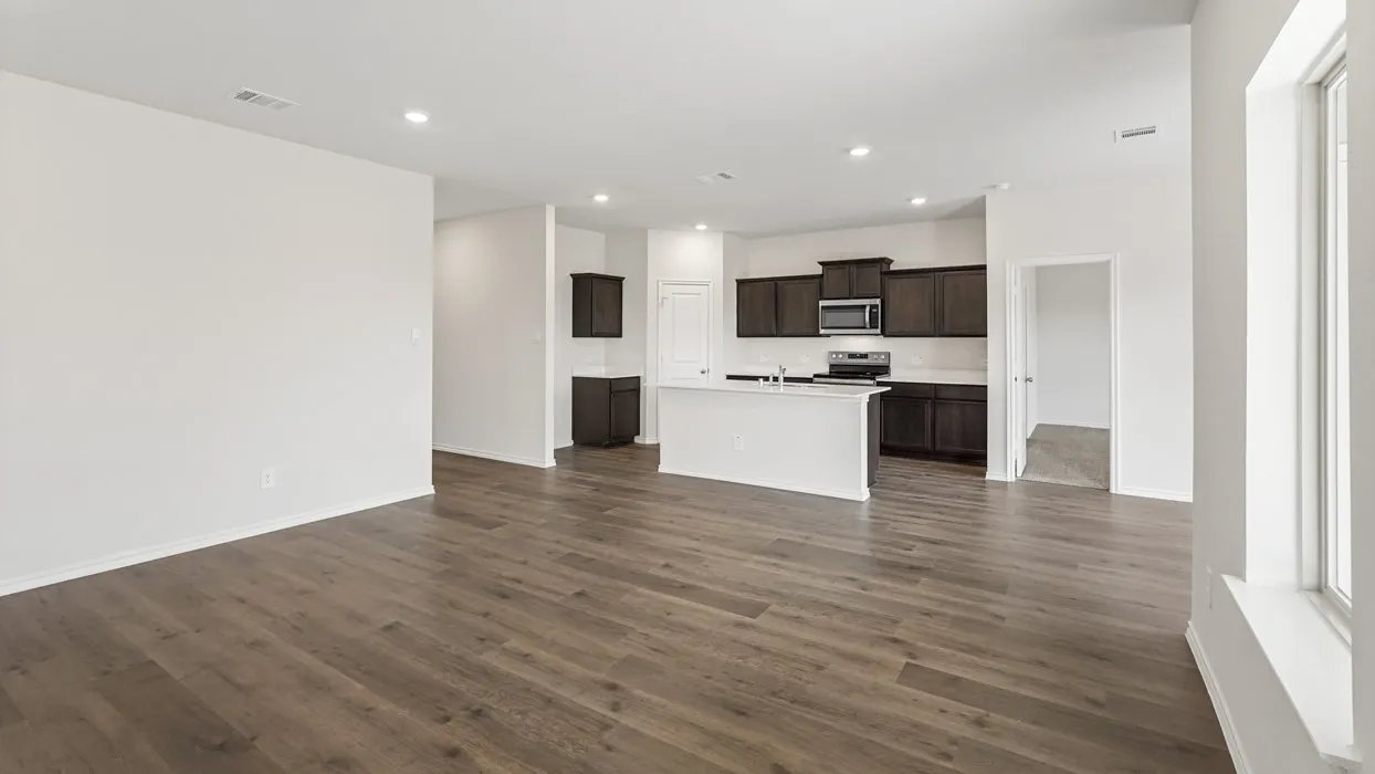 Wood-finish flooring, recessed lighting, white walls, dark wood-finish cabinetry, and a kitchen island with a white countertop