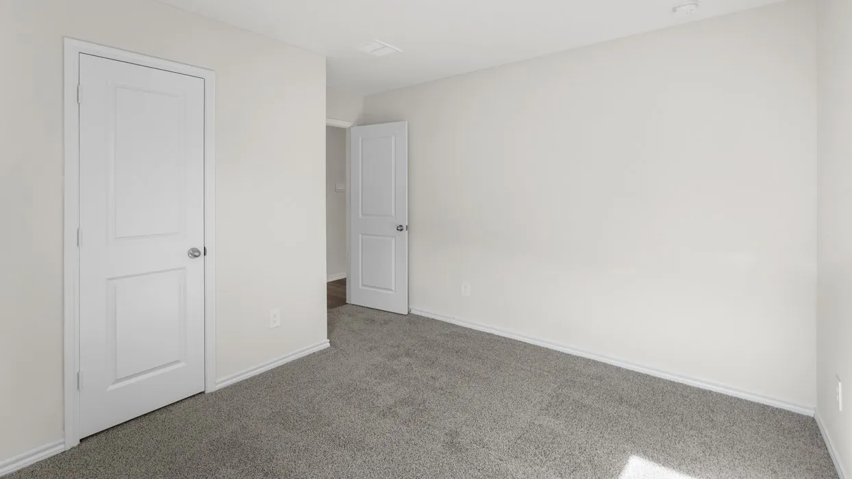 Neutral wall finish, two-panel interior doors, and gray carpeting