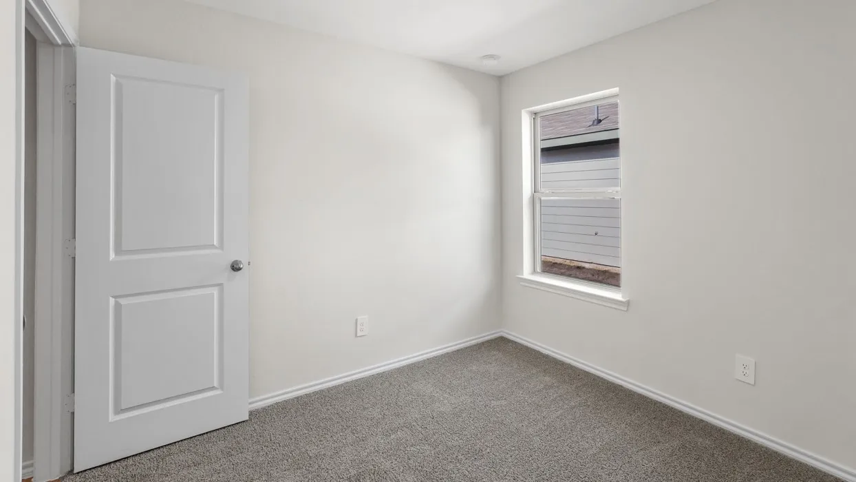 Neutral wall color, carpet flooring, window with trim, two-panel door with hardware, and white baseboards