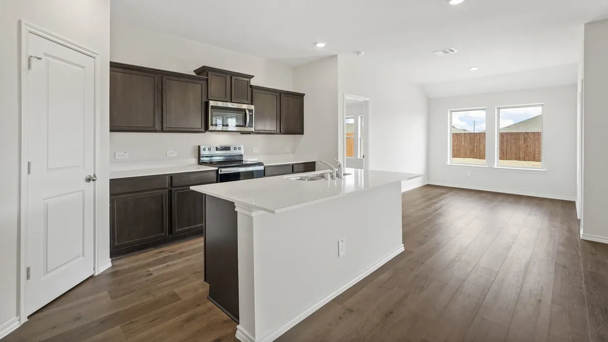 Open-concept living area featuring wood-finish flooring, white walls, and a kitchen island with a built-in sink