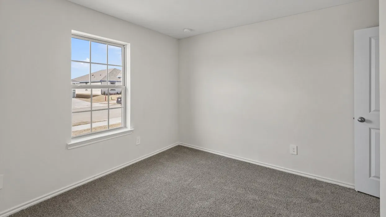 Bright room featuring a grid-pattern window, neutral gray carpeting, white baseboards, and a white paneled door