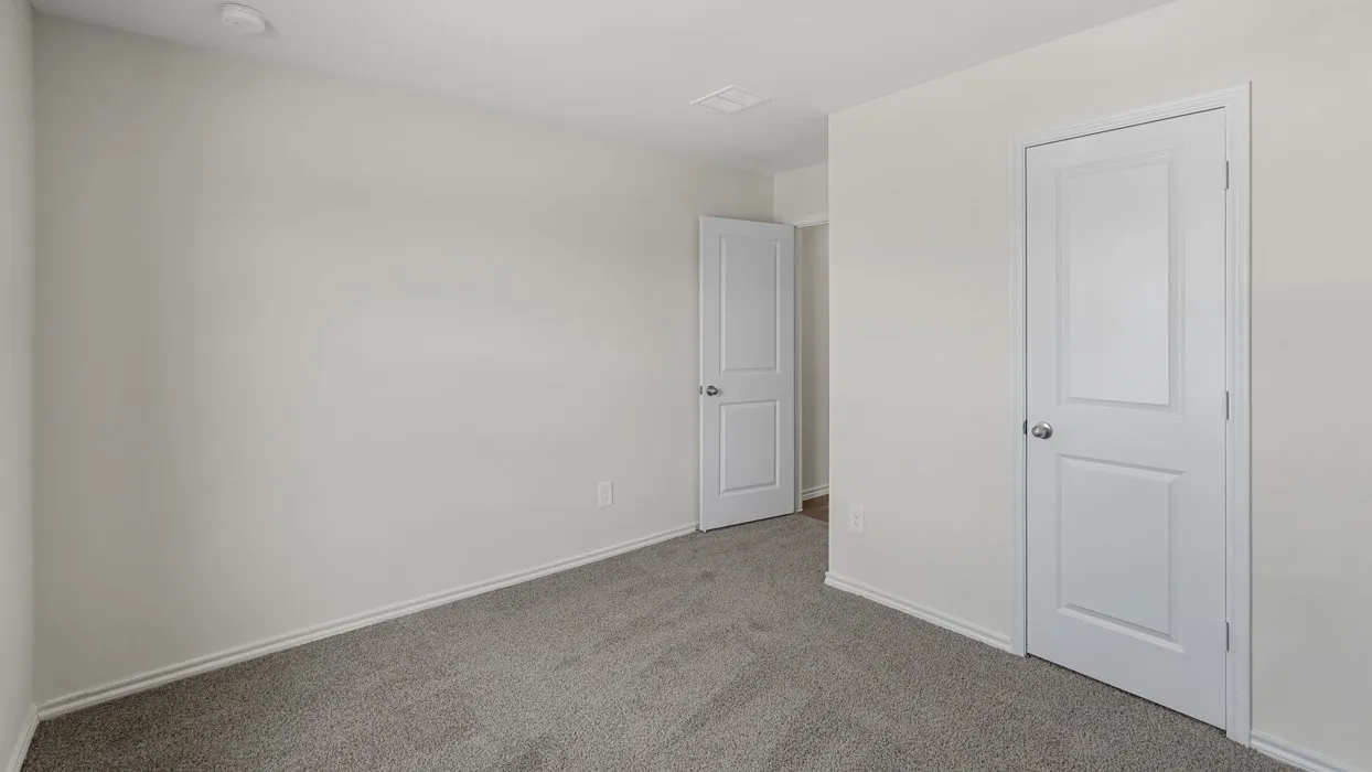 Carpeted room featuring light gray wall paint, white trim, and white paneled doors with chrome hardware