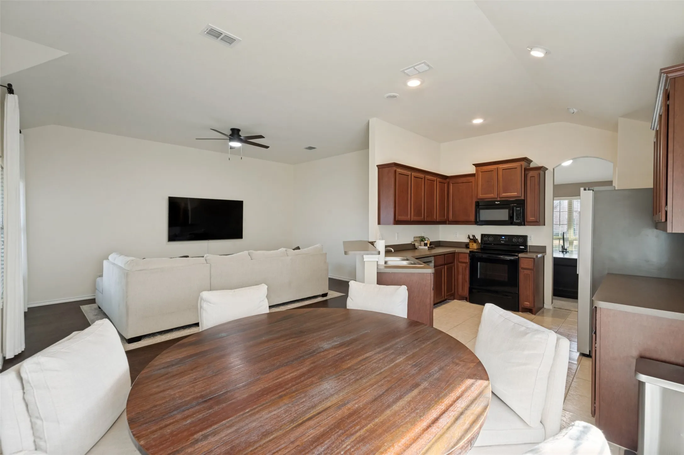 Kitchen with wood-finish cabinetry and black appliances, complemented by a breakfast bar