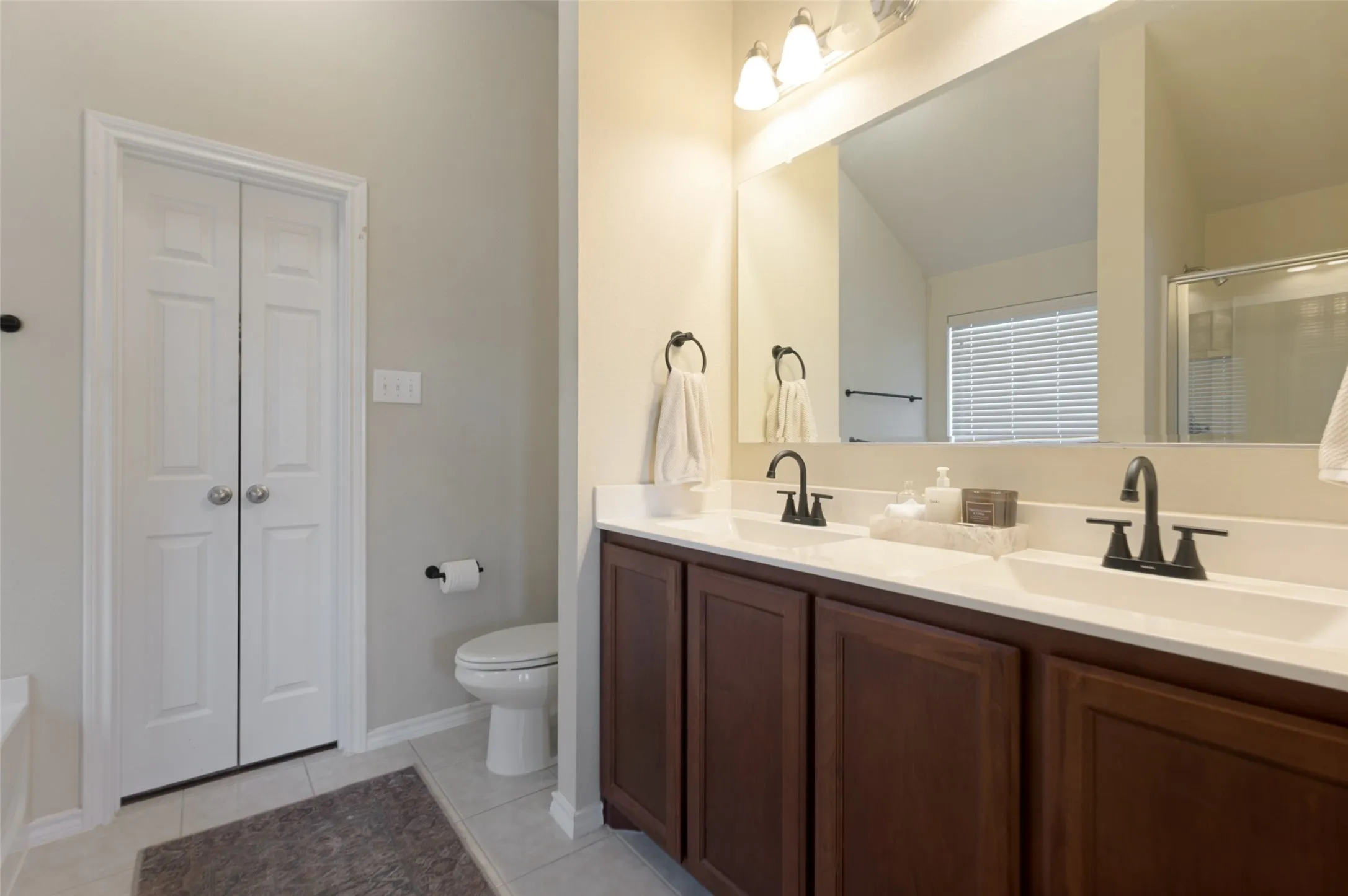 Double vanity with integrated sinks, dark wood-finish cabinetry, and matte black fixtures