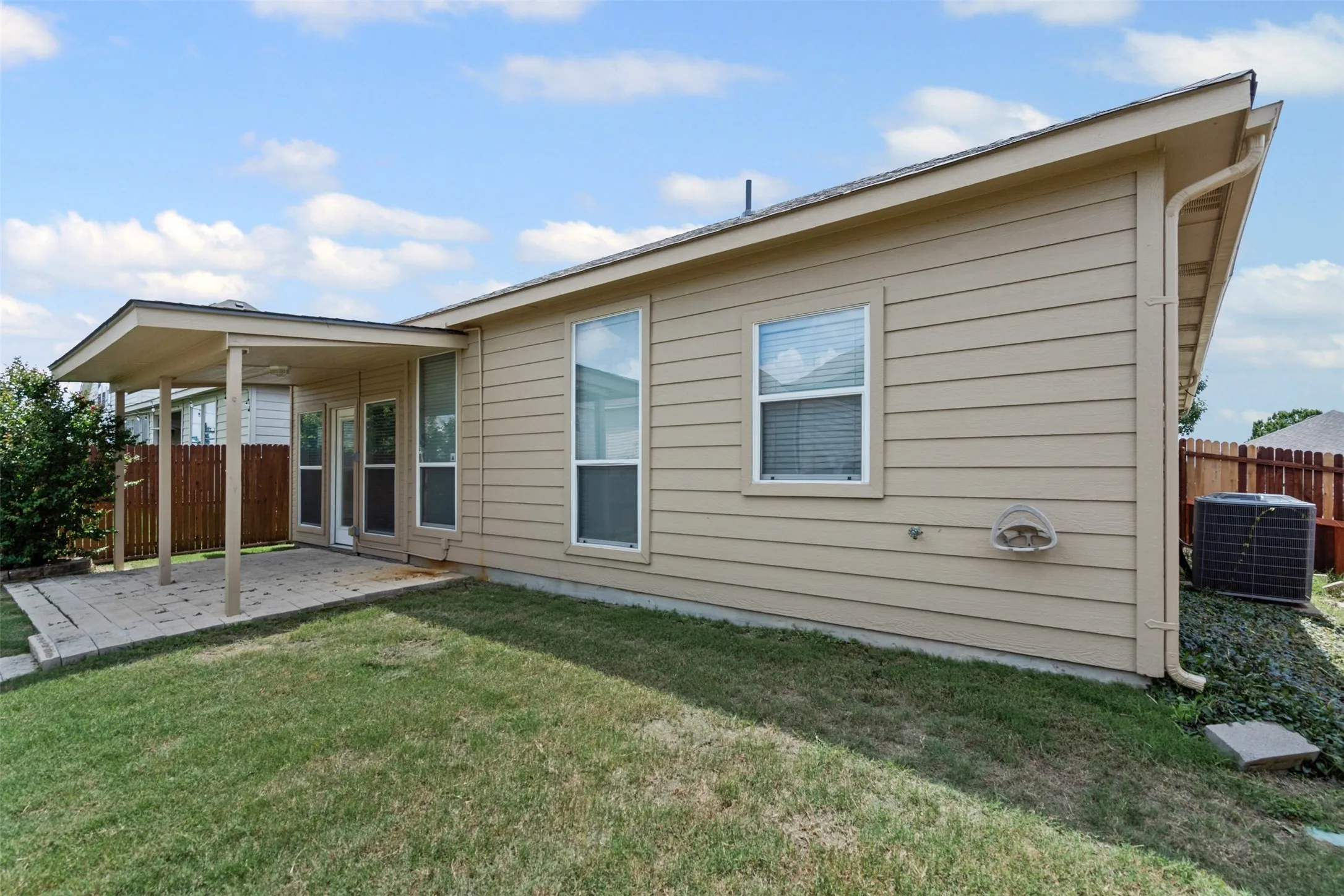Covered patio with a concrete slab, a manicured lawn, and exterior siding
