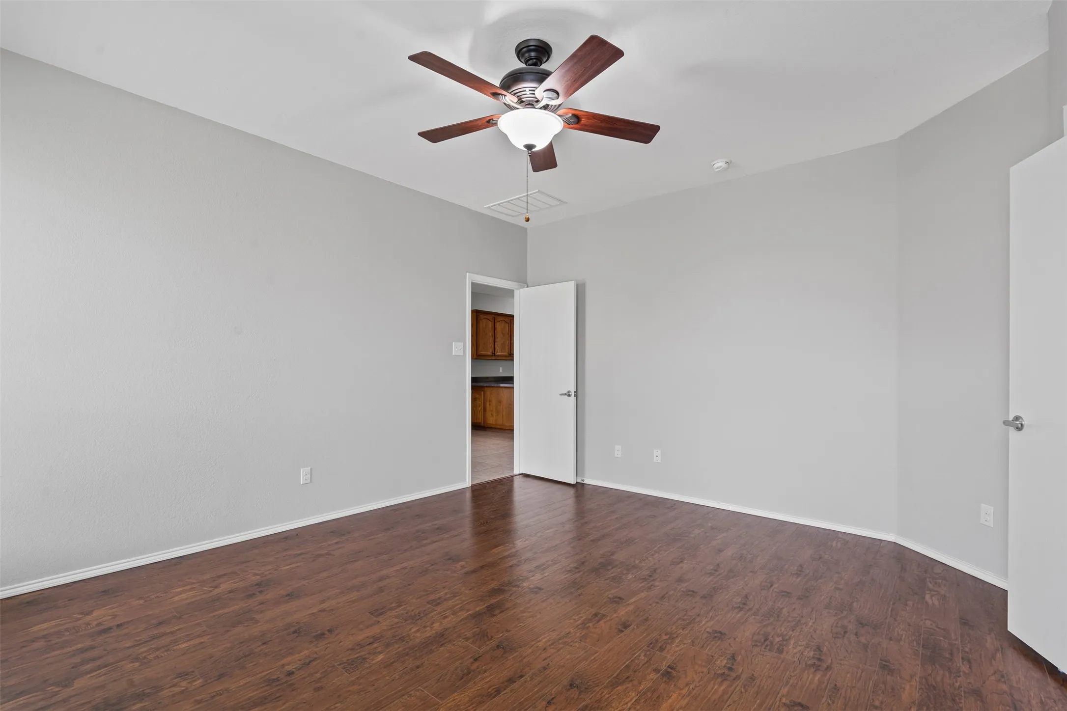 Wood-finish flooring, neutral wall tones, and a ceiling fan with integrated lighting