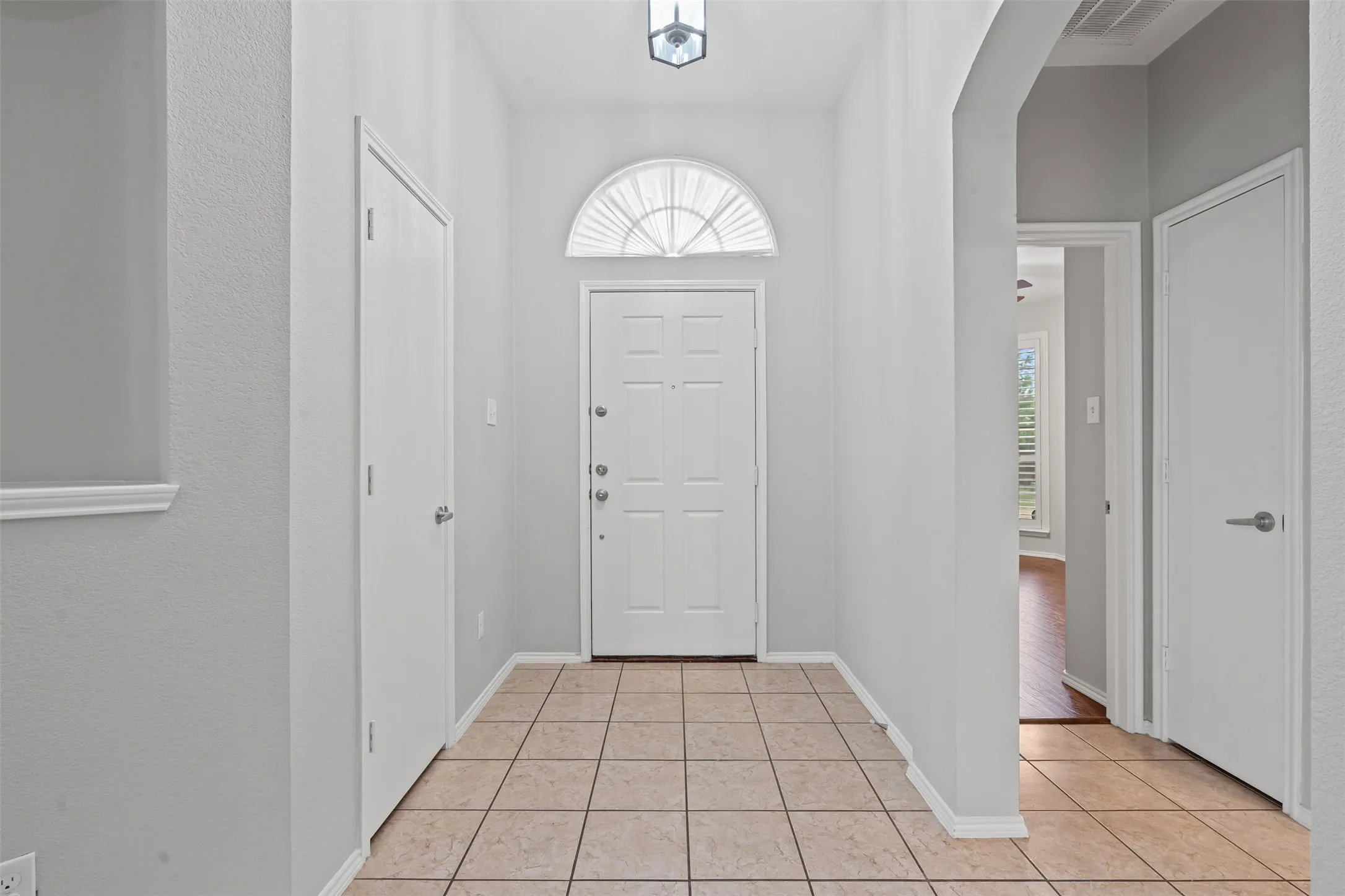 Recessed entrance with tiled flooring, an arched transom window, and a flush-mount ceiling fixture