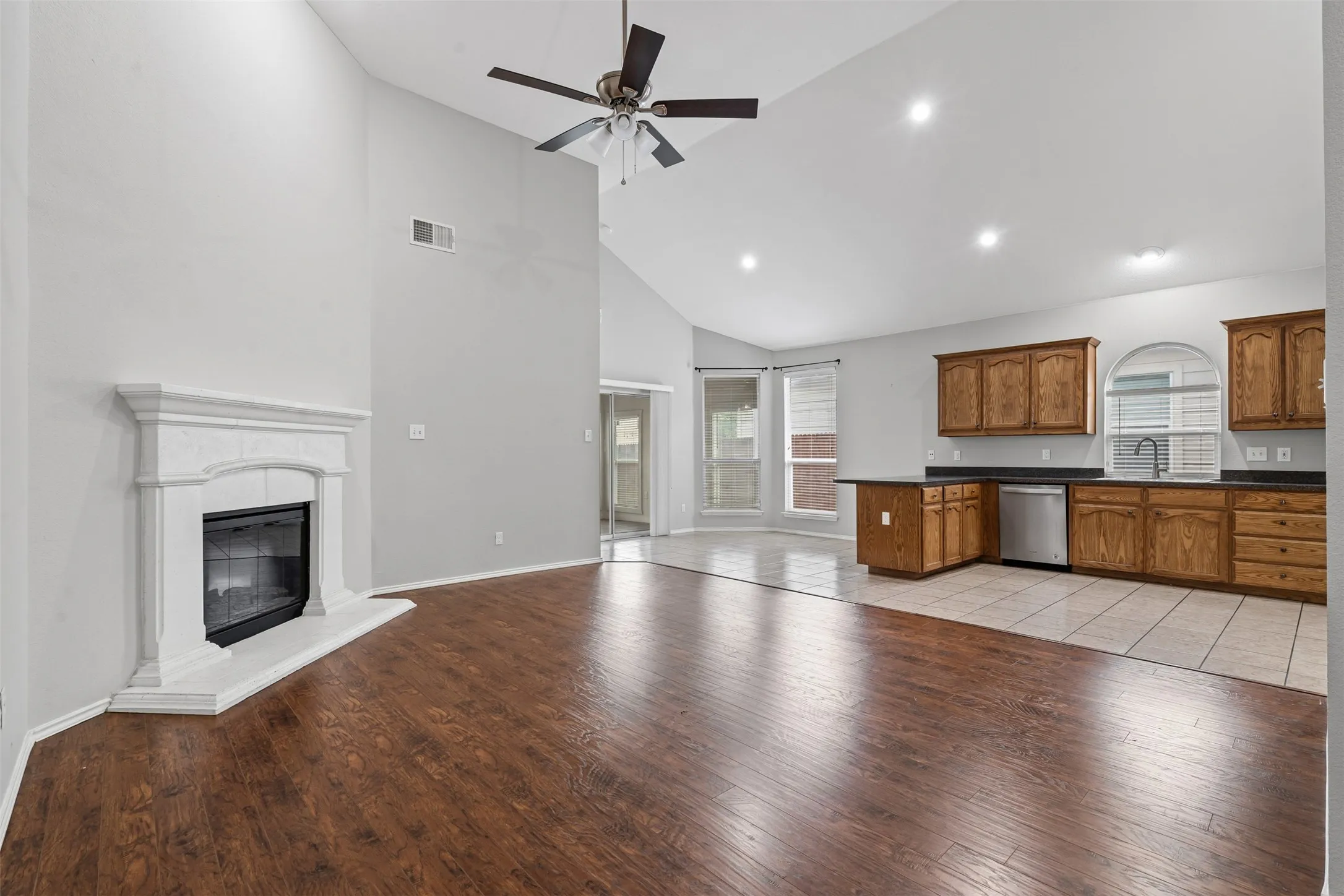 Open concept living area featuring a vaulted ceiling and wood-finish flooring