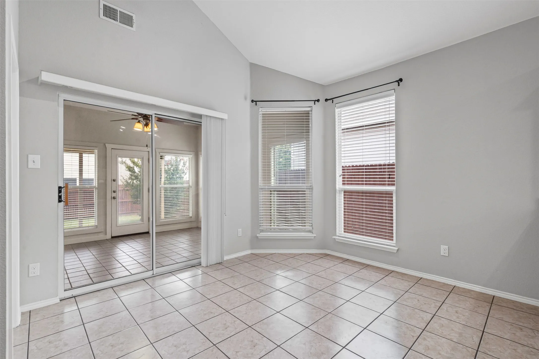 Vaulted ceiling, tile flooring, corner window configuration, and sliding glass doors