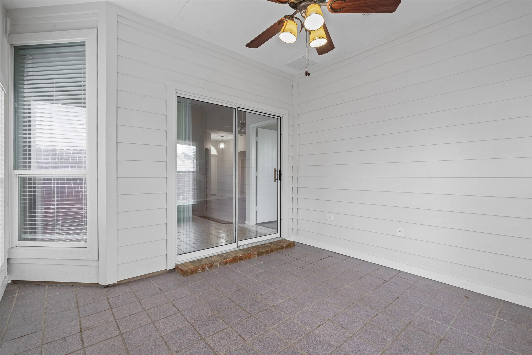 Screened porch with durable tile flooring and a ceiling fan