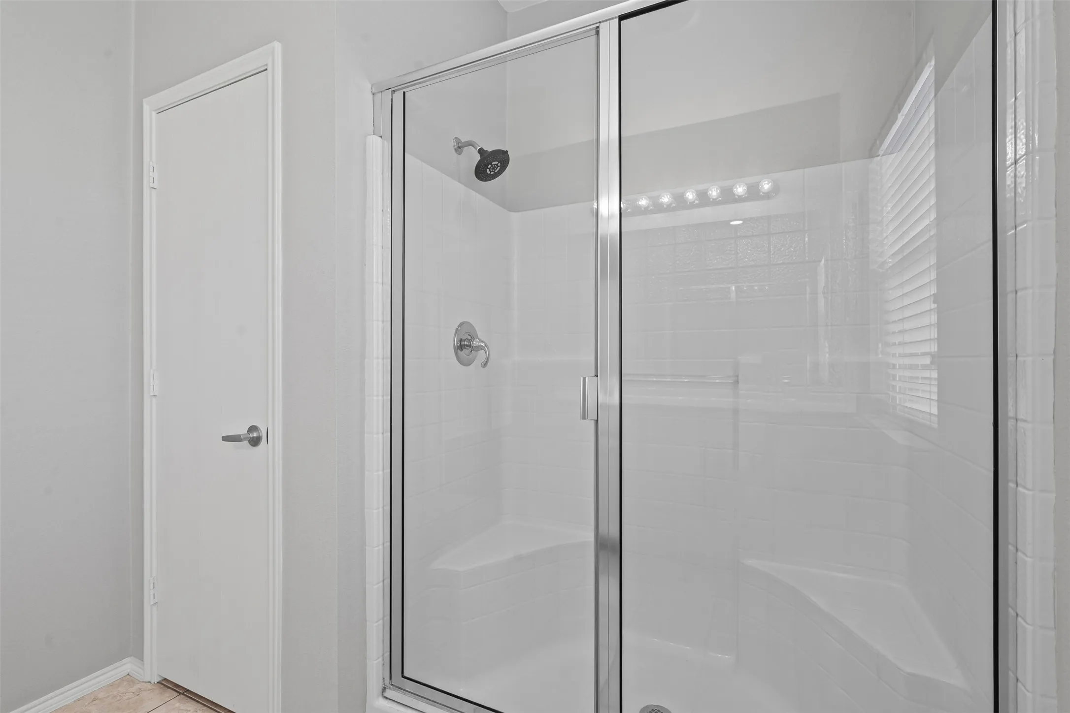 Shower enclosure with clear glass sliding doors, tiled walls, built-in seating, and a rain showerhead