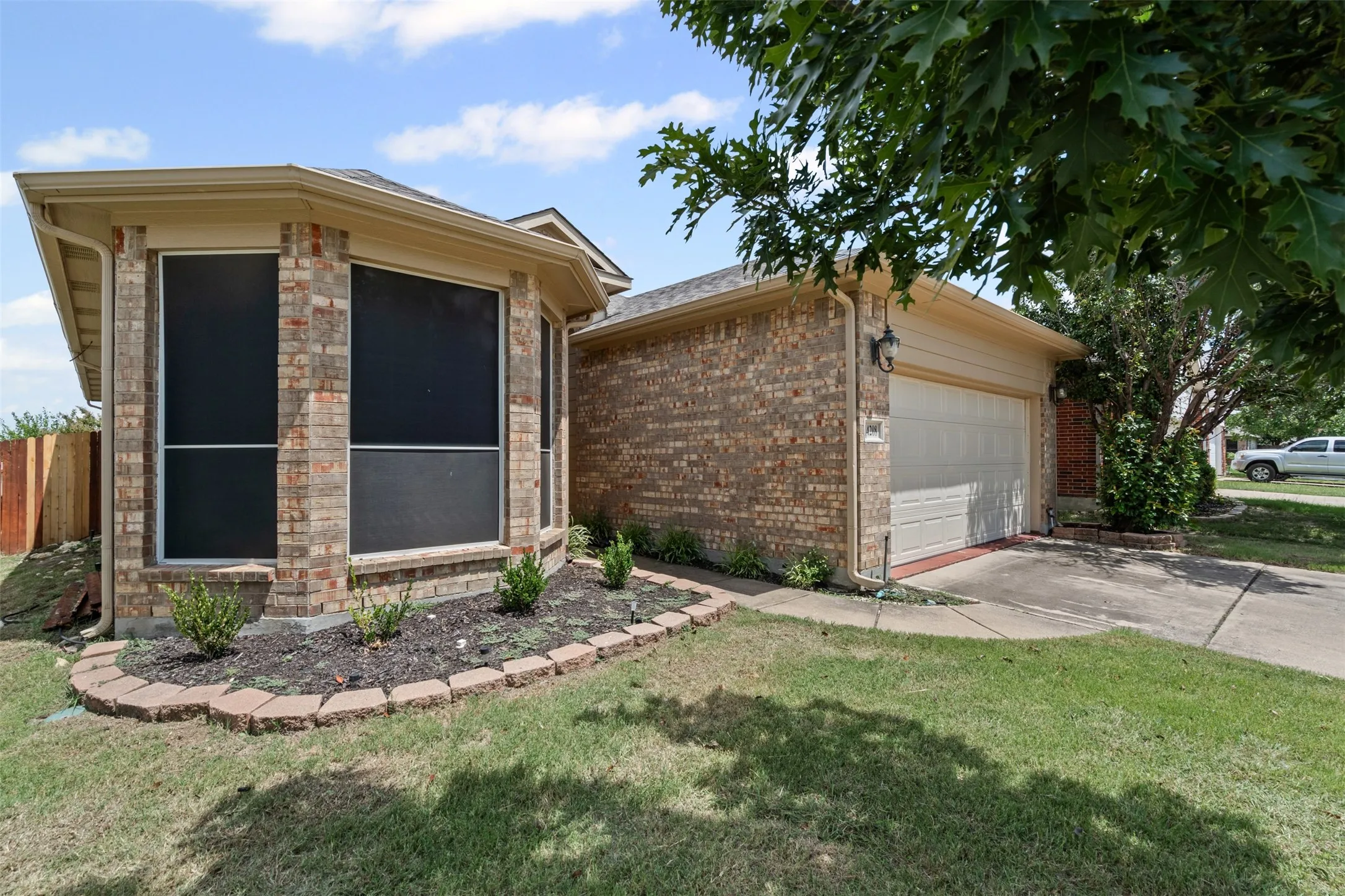 Brick exterior with a two-car garage, bay windows, and a landscaped garden bed