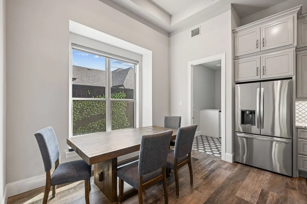 Wood-finish flooring, recessed ceiling, large window, stainless steel refrigerator, and custom cabinetry