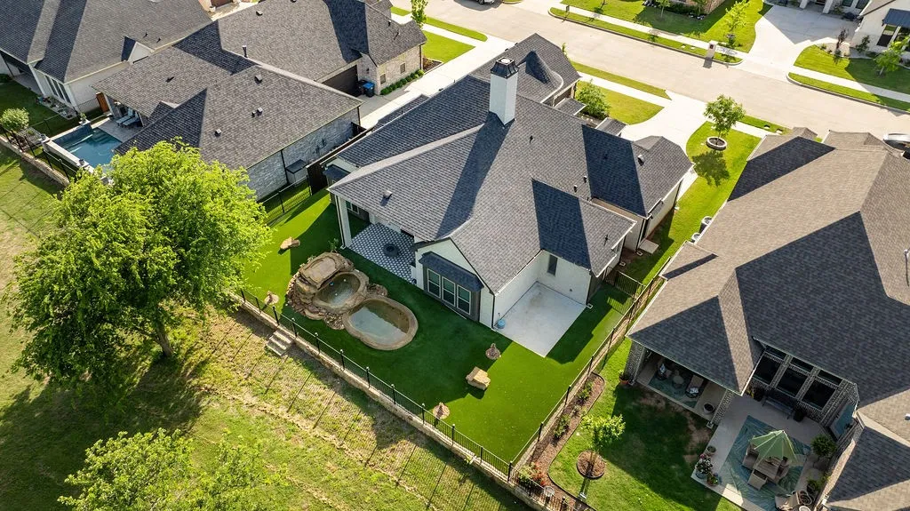 Rear exterior featuring a covered patio, extensive artificial turf, and a two-tier water feature