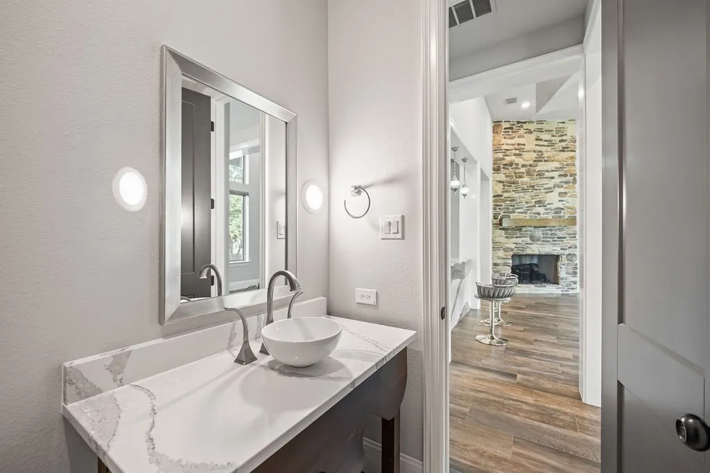 Vanity with a vessel sink, stone-finish countertop, and framed mirror